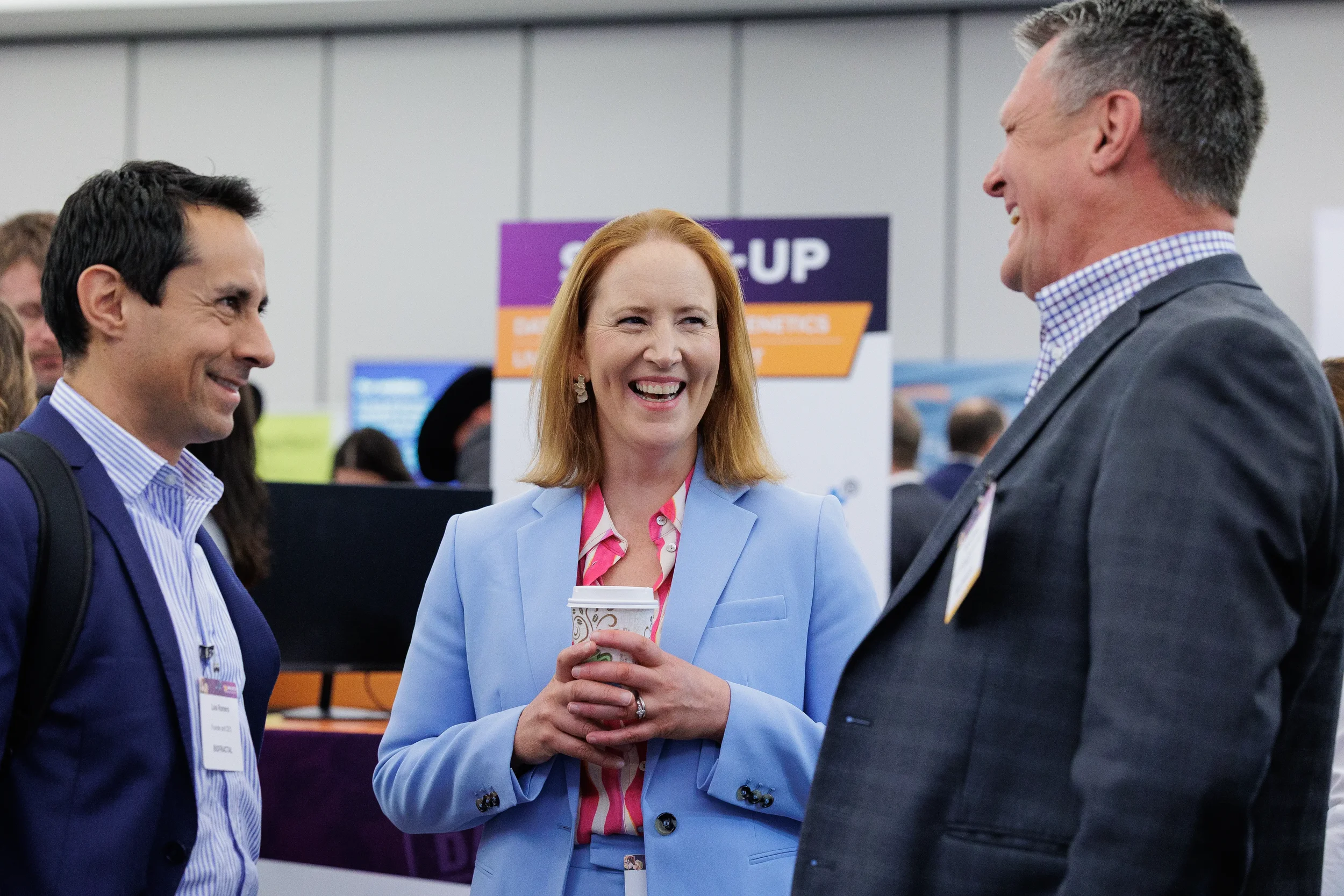 Attendees laugh during conversation at exhibitor booth at Chicago corporate conference