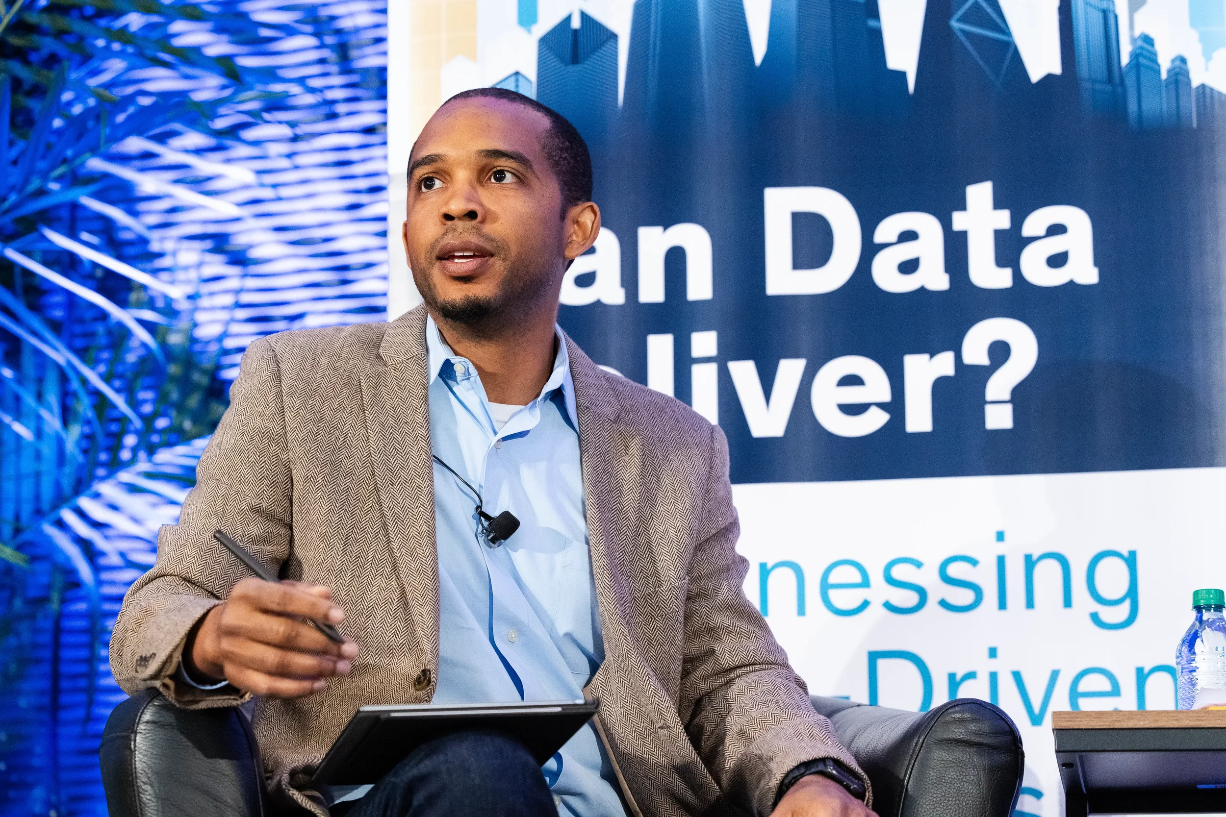 Panelist gestures while seated during stage discussion at Orlando industry conference