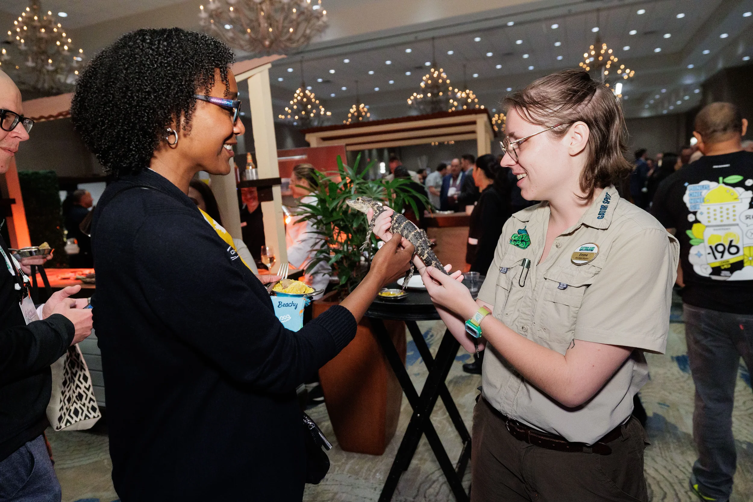 Attendee laughs while touching alligator held by wildlife handler at Chicago corporate conference reception