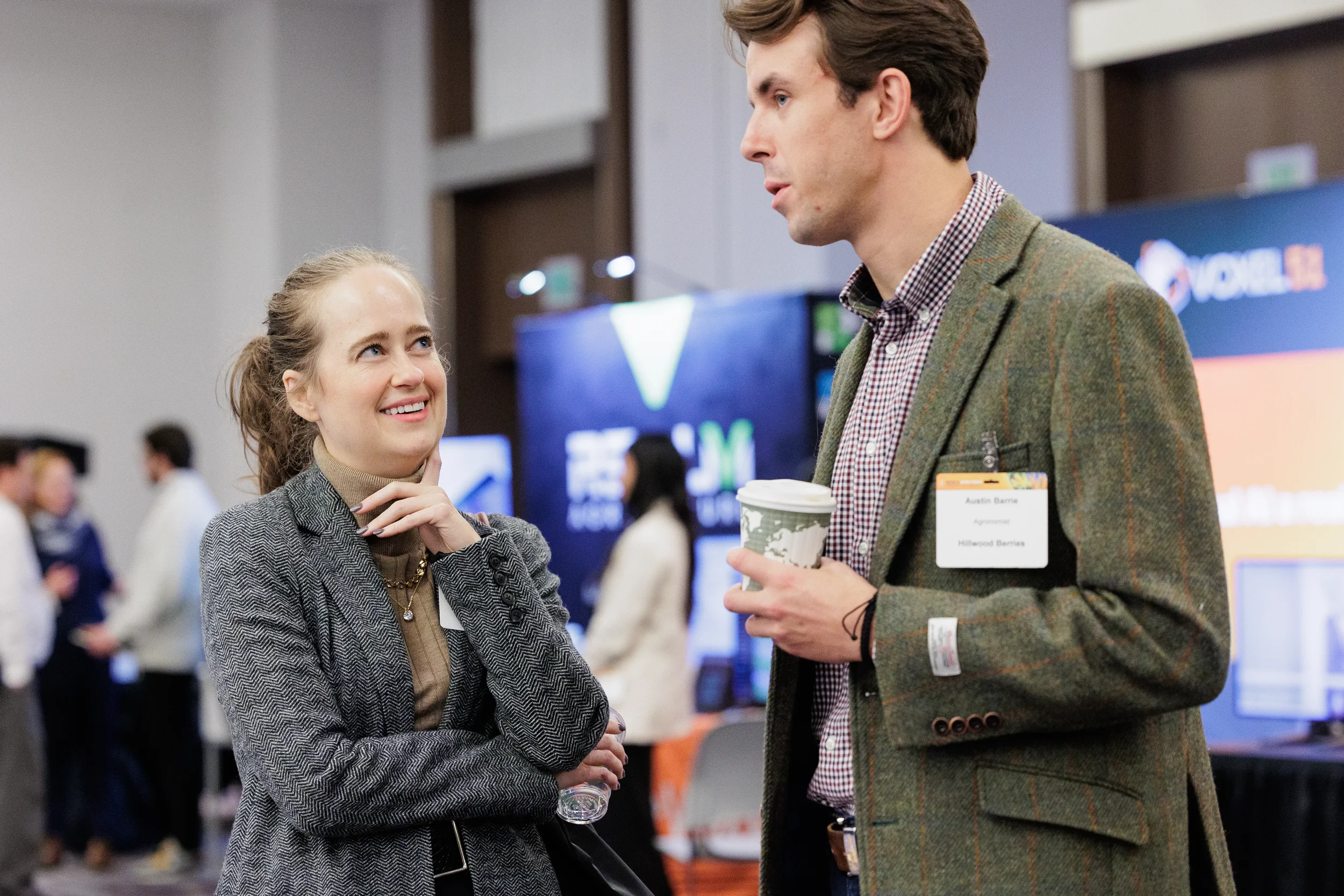 Two smiling badged attendees converse over coffee on Orlando corporate conference expo floor