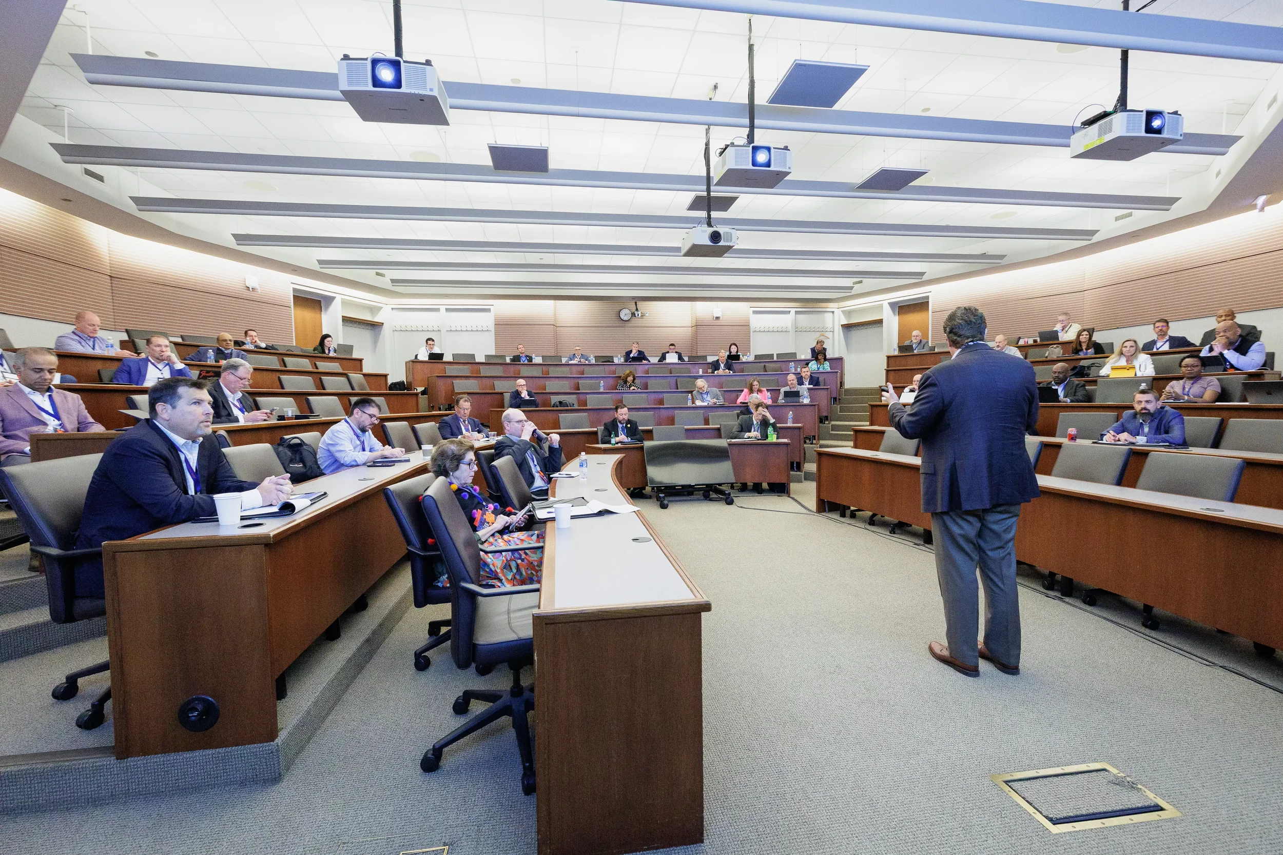 Speaker addresses full tiered classroom of seated attendees at Orlando corporate conference session