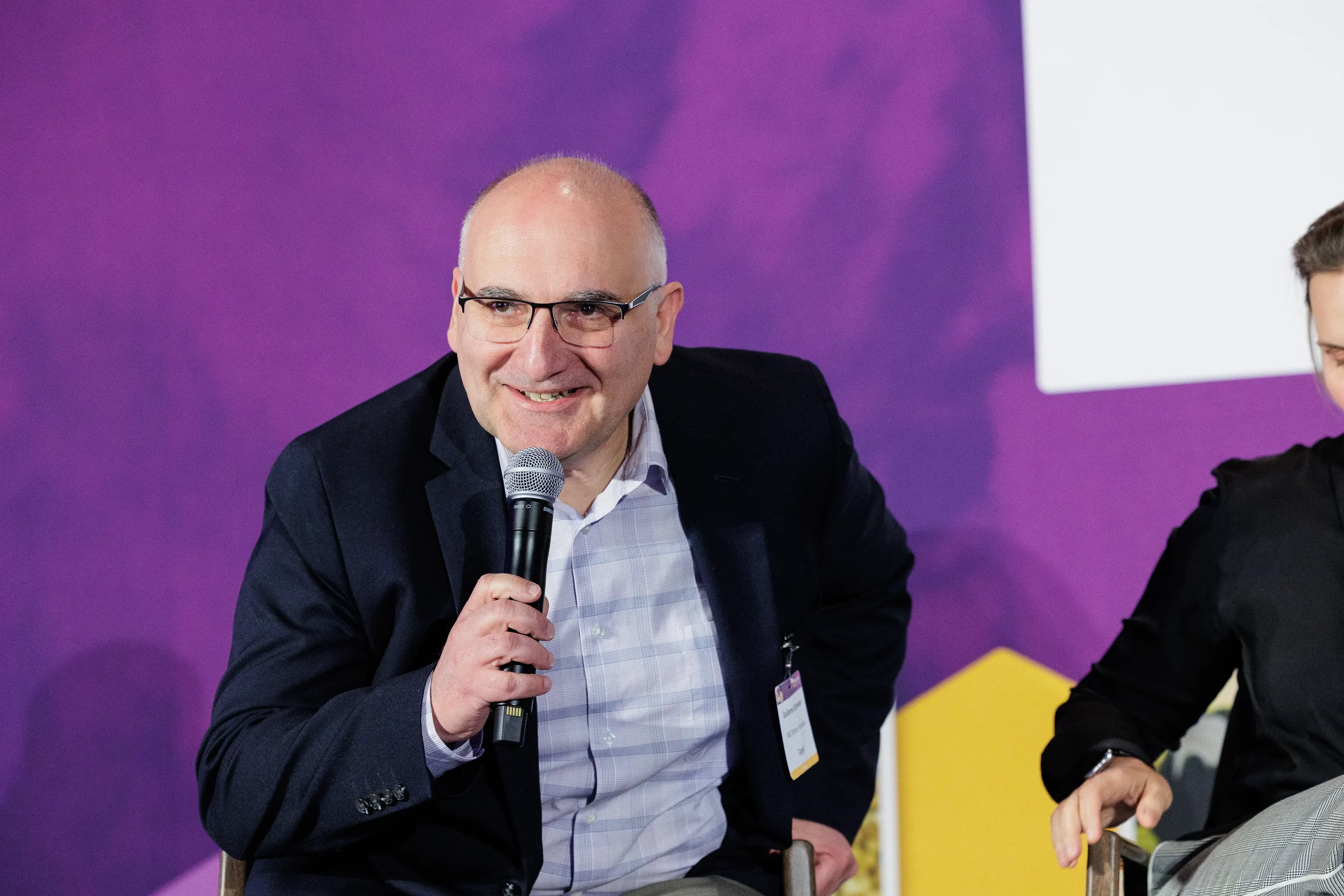 Panelist smiles while speaking into microphone during seated discussion at Orlando summit