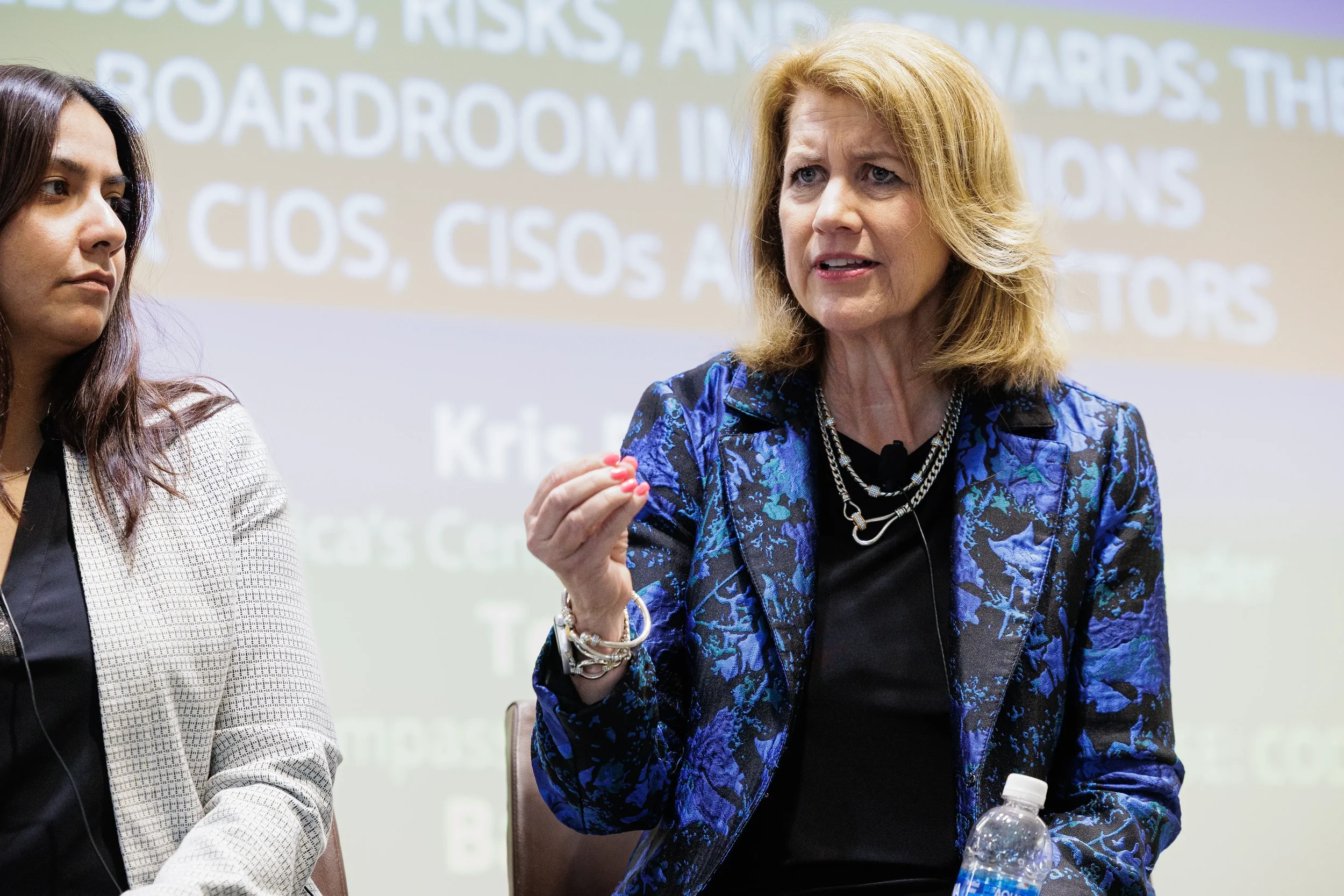 Female panelist gestures while speaking on stage in front of projection screen at Chicago industry conference