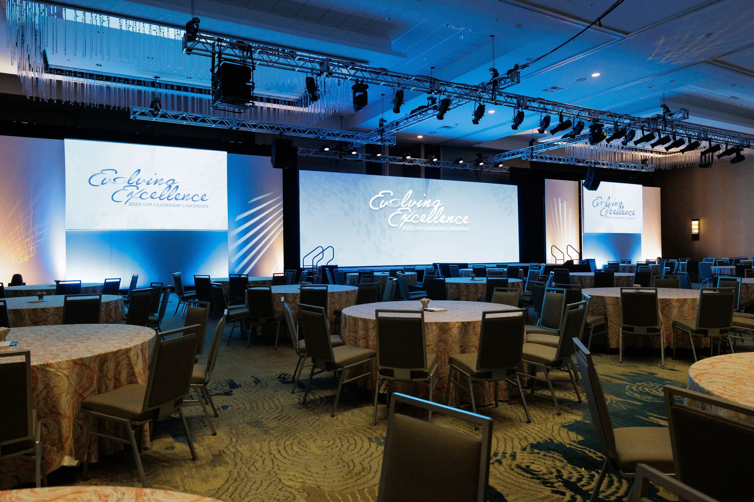 Empty ballroom with branded screens and blue stage lighting set up for Chicago corporate conference