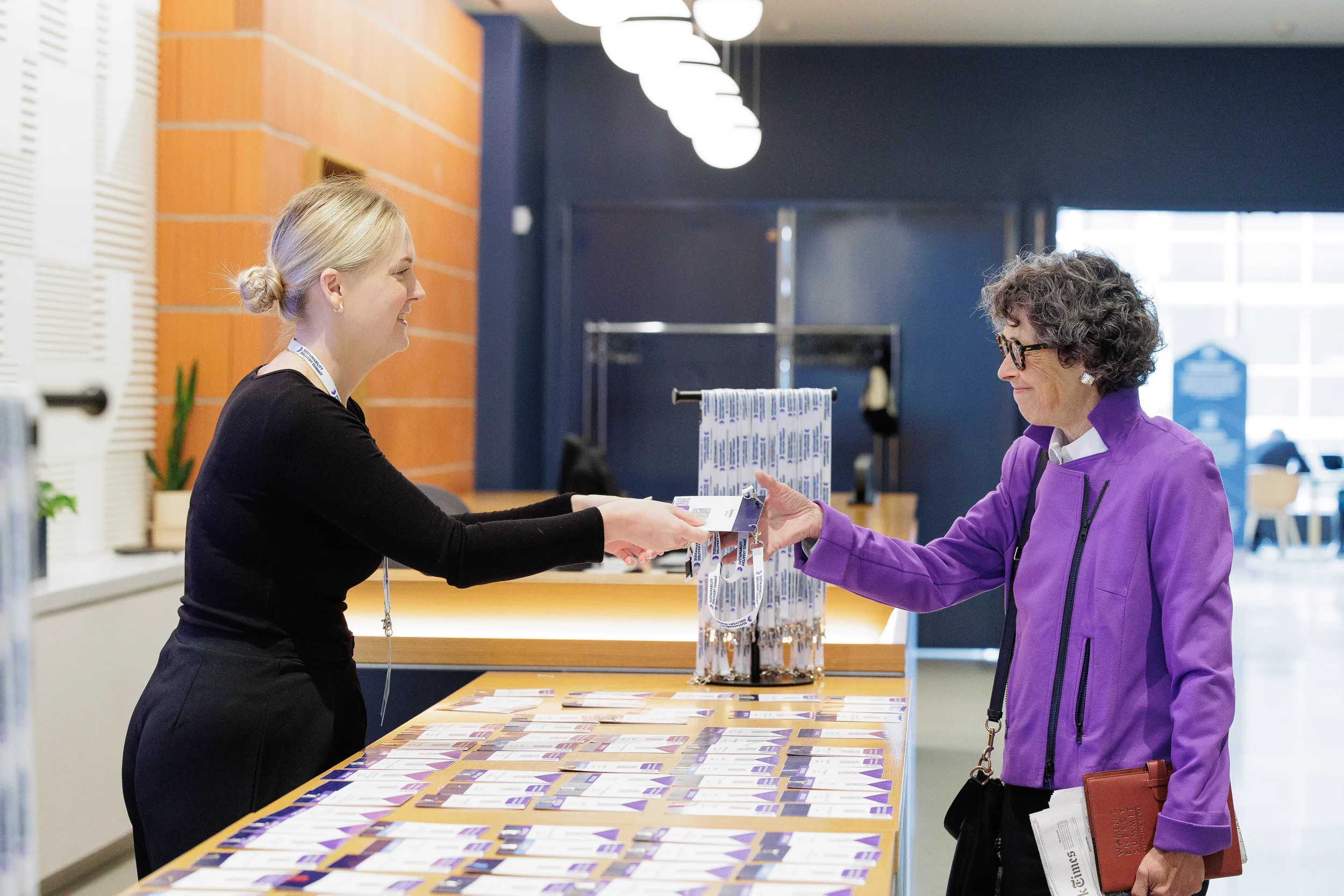 Staff member hands badge to attendee at registration desk during Orlando corporate event check-in