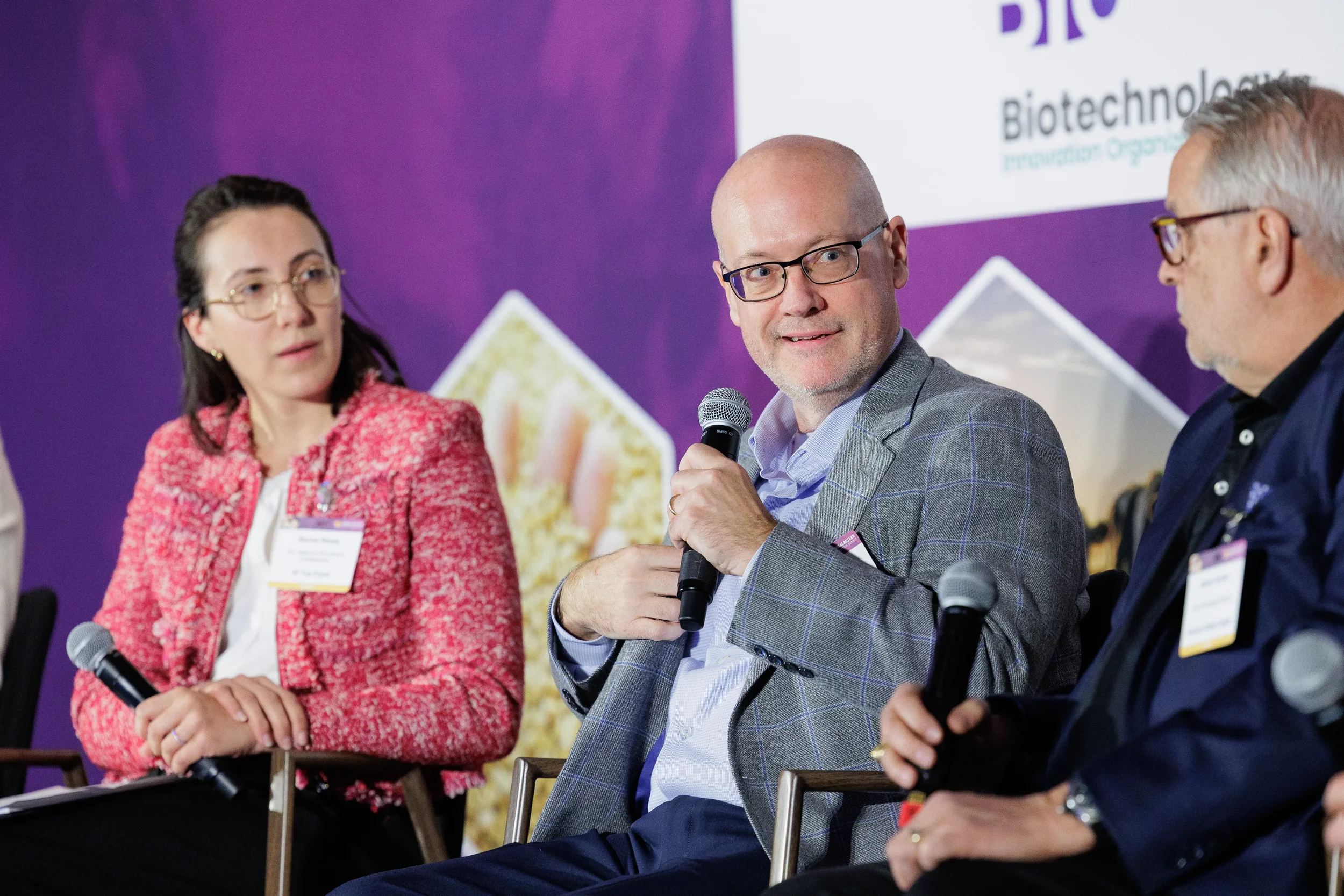 Panelist gestures while speaking into microphone during seated discussion at Orlando summit