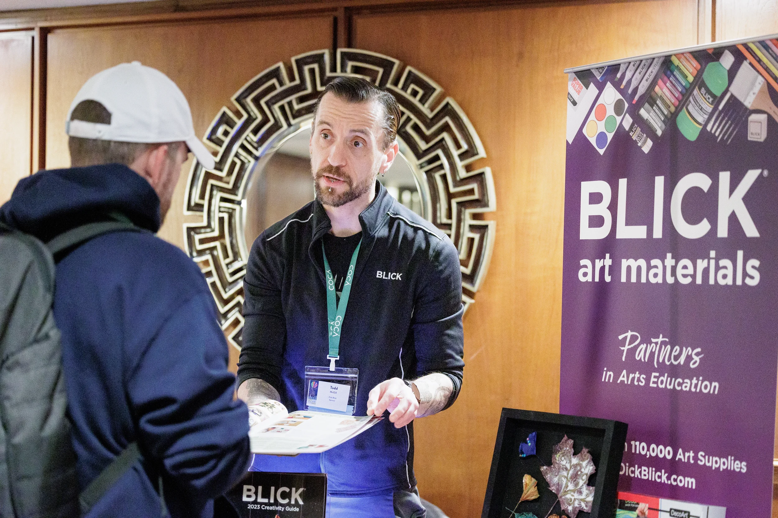 Exhibitor shares catalog with attendee at sponsor booth during Orlando nonprofit conference event