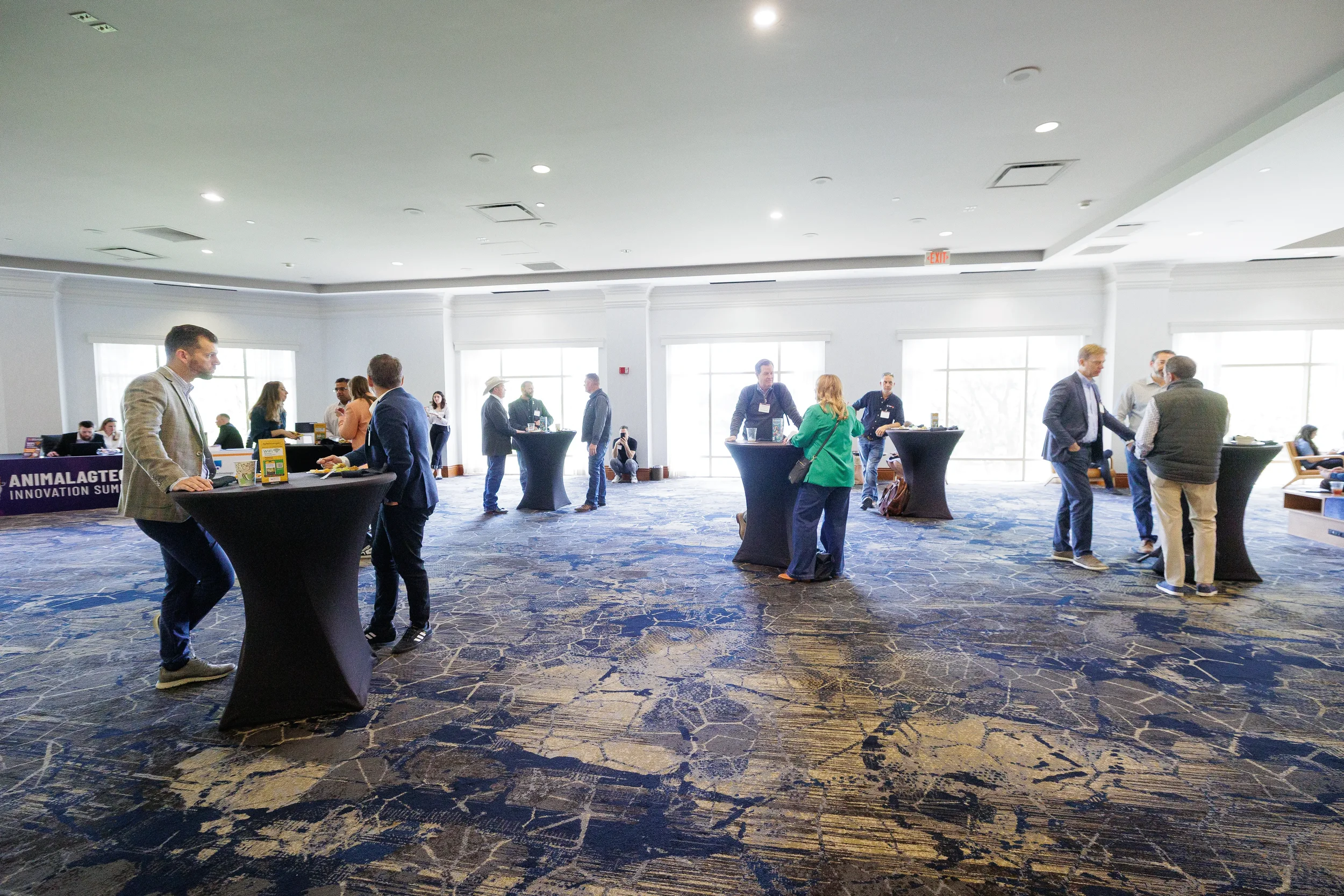 Attendees network at standing tables in ballroom during Orlando corporate conference