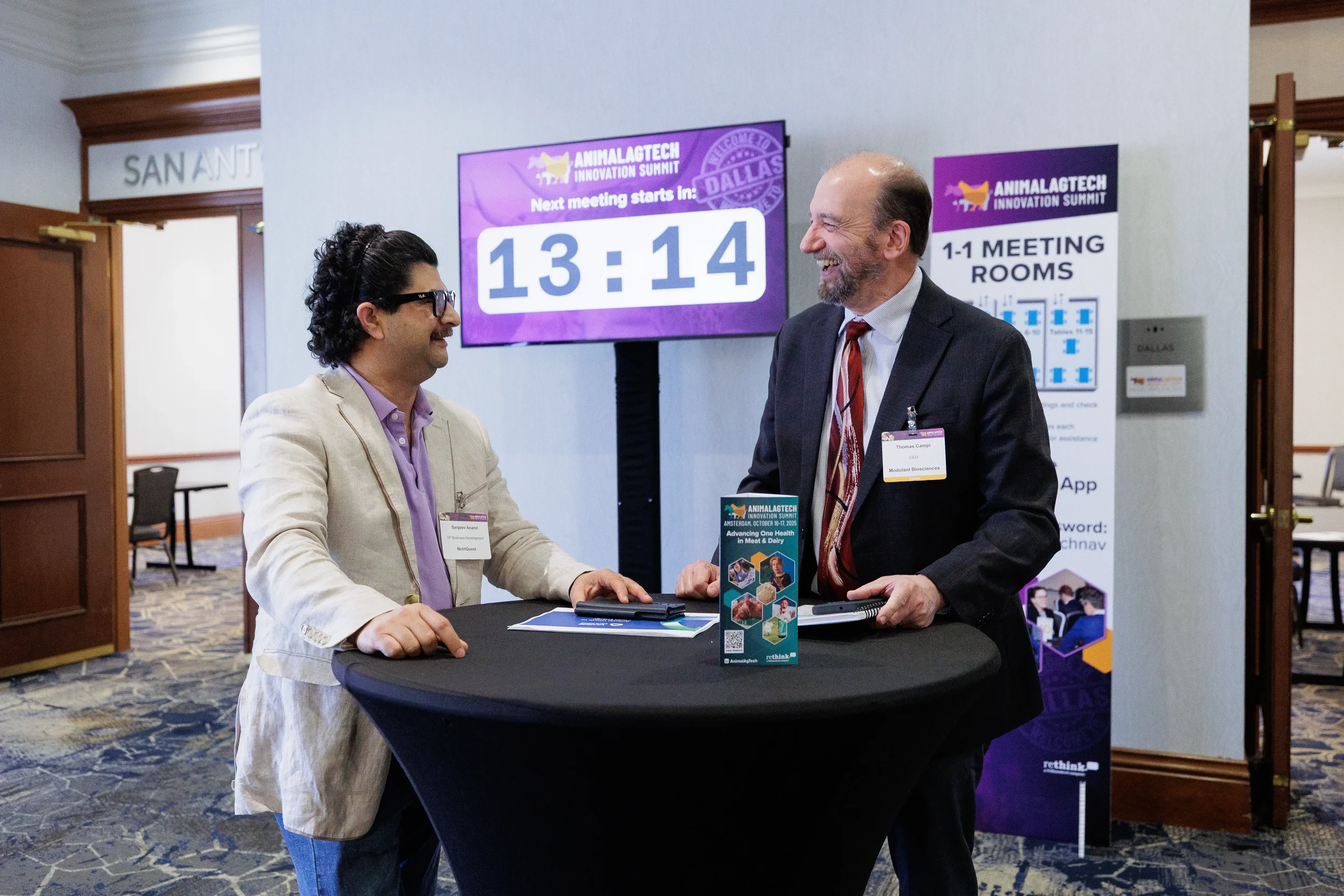 Two attendees laugh during conversation at standing table at Orlando industry conference