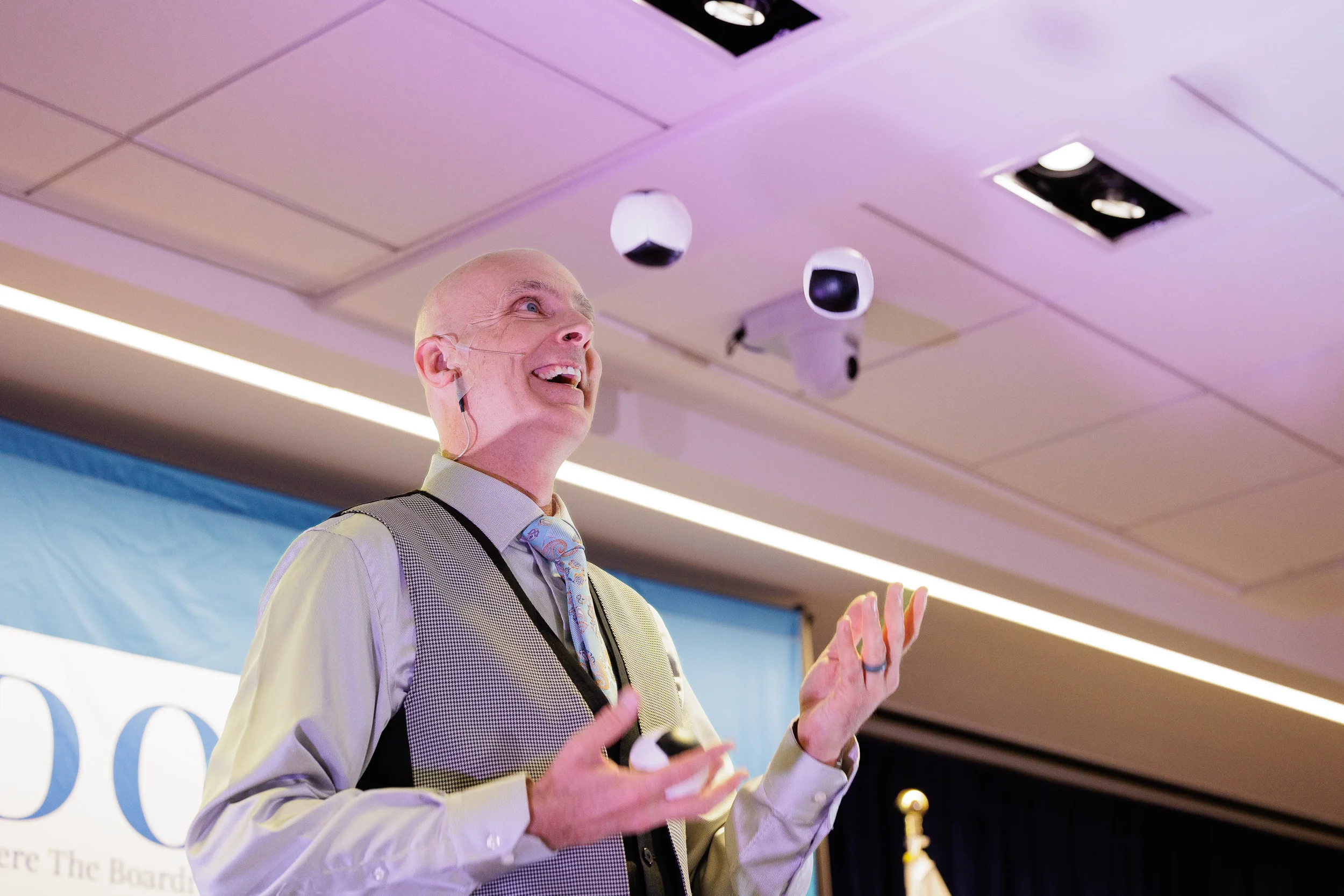 Smiling entertainer tosses juggling balls in air on stage at Orlando corporate conference event