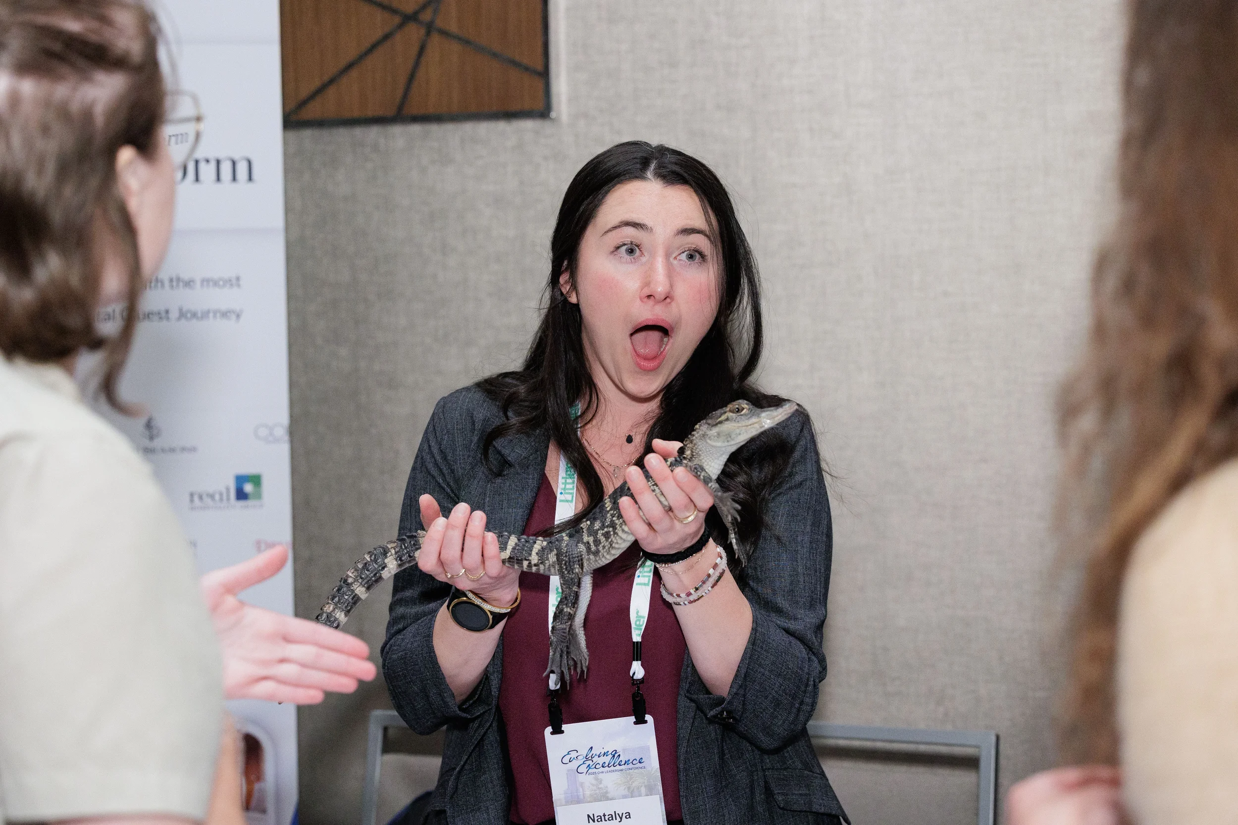 Surprised attendee with lanyard holds small alligator with wide eyes at Chicago corporate conference