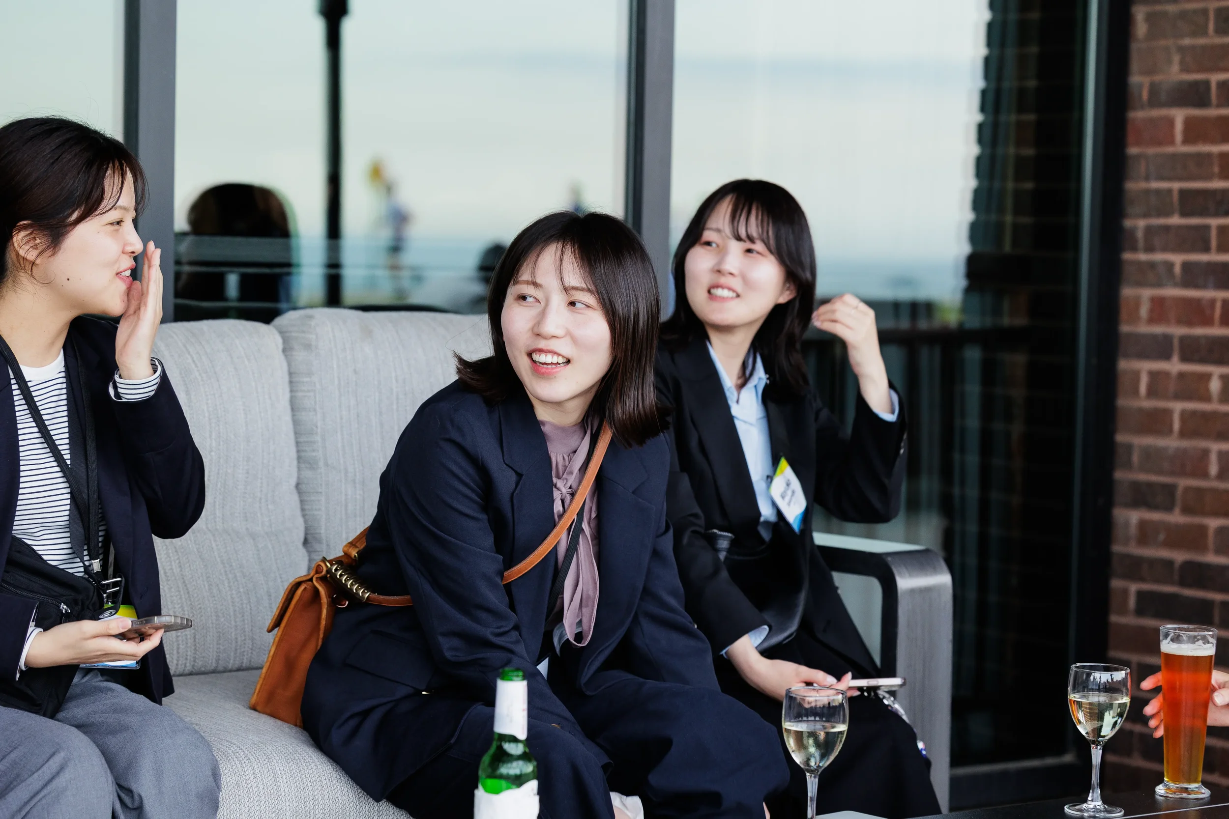 Three colleagues share a laugh on terrace sofa with drinks at Orlando networking reception
