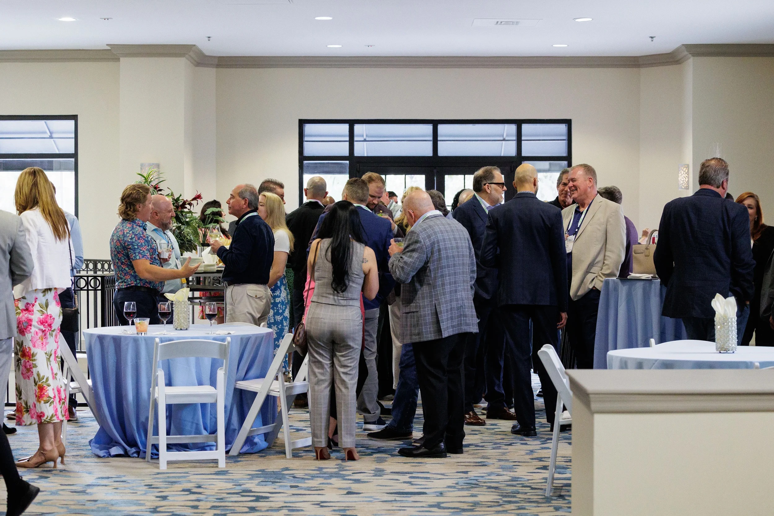 Large group of attendees network over drinks at cocktail tables during Orlando corporate conference reception