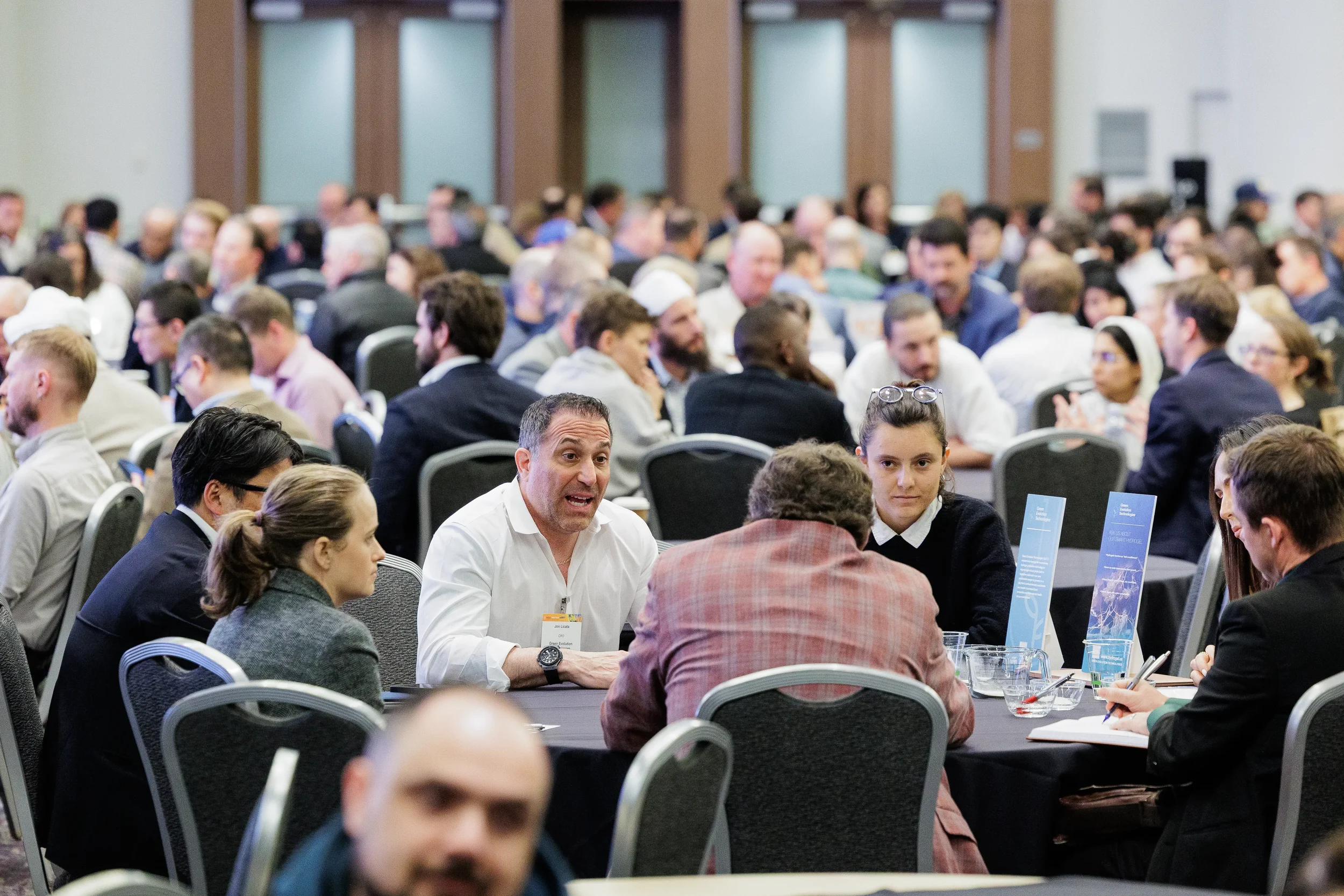 Packed ballroom of badged attendees seated at round tables during Orlando industry conference networking session