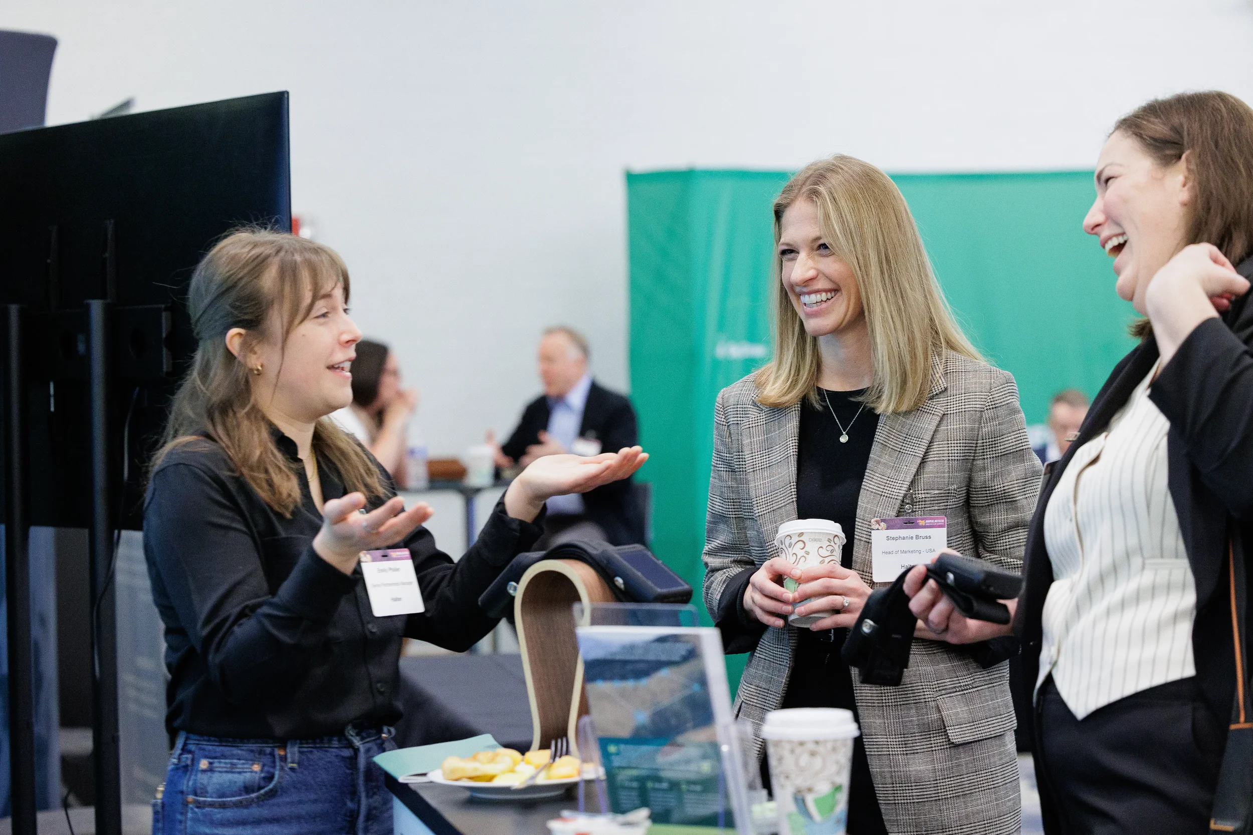 Three attendees laugh during conversation at exhibitor booth at Orlando corporate conference