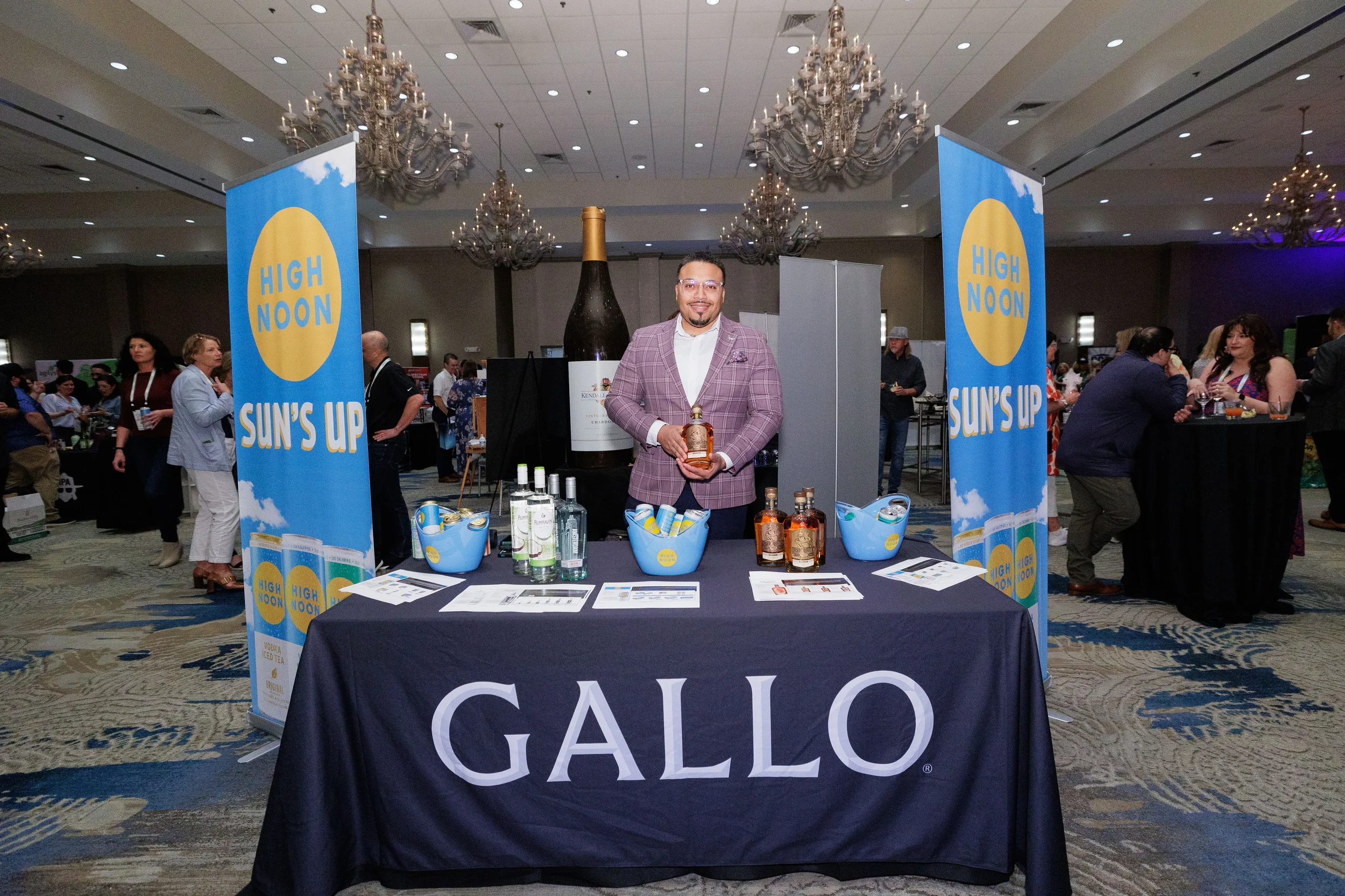 Booth staff poses with branded banners and oversized bottle display in Orlando corporate conference ballroom