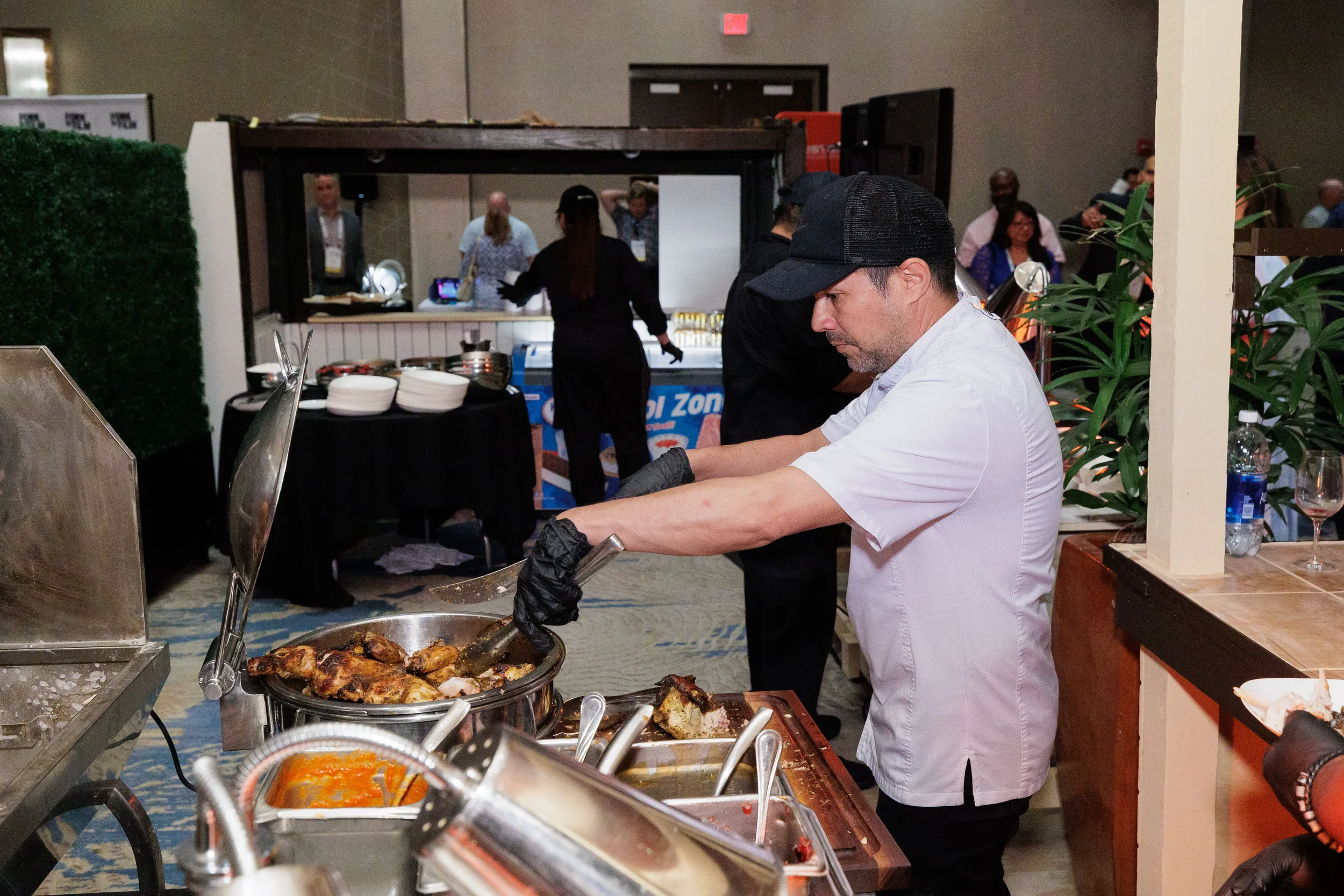 Chef in cap tends to grilled food at live cooking station during Chicago corporate conference expo reception