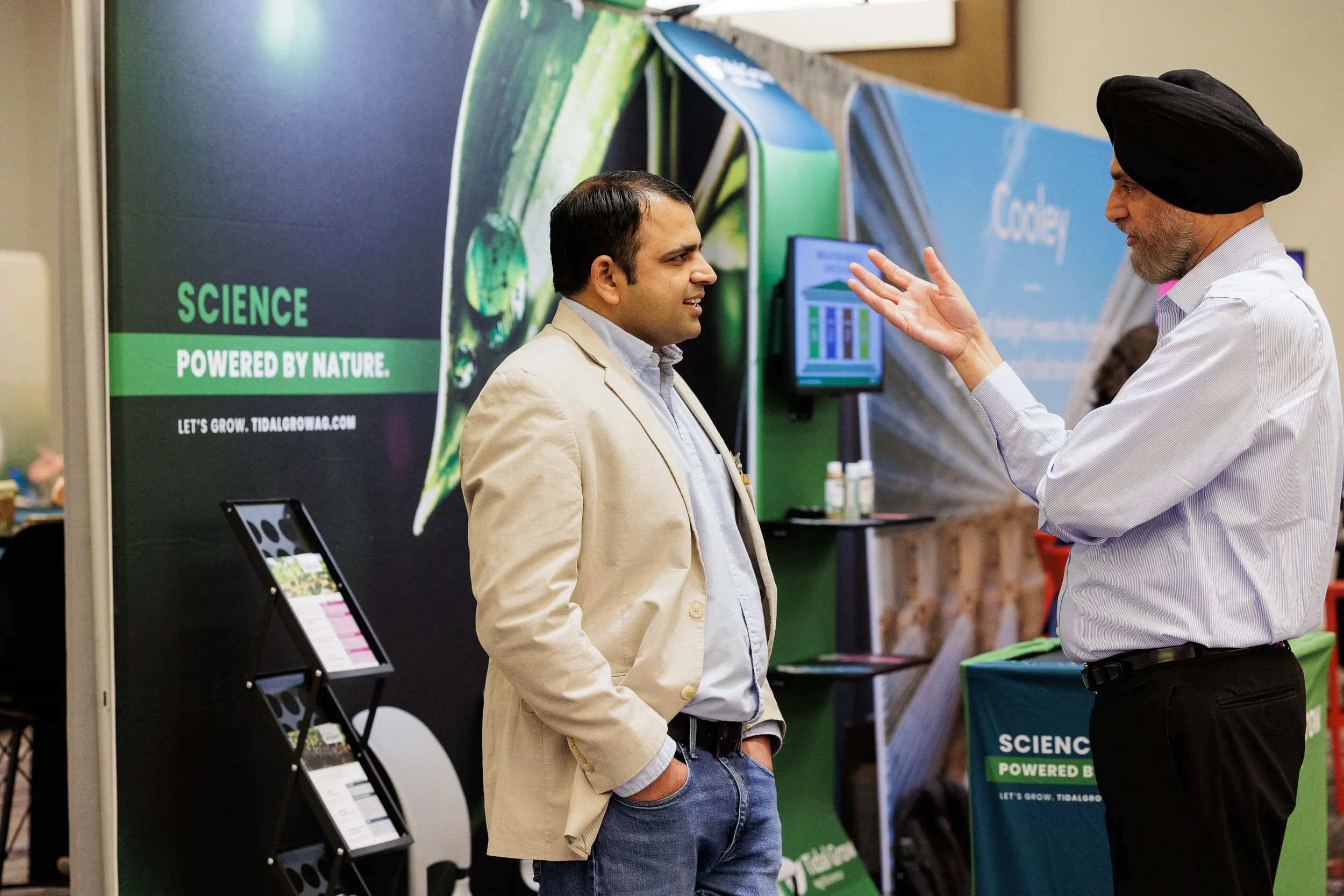 Two badged attendees in conversation at agtech exhibitor booth on Orlando industry conference trade show floor