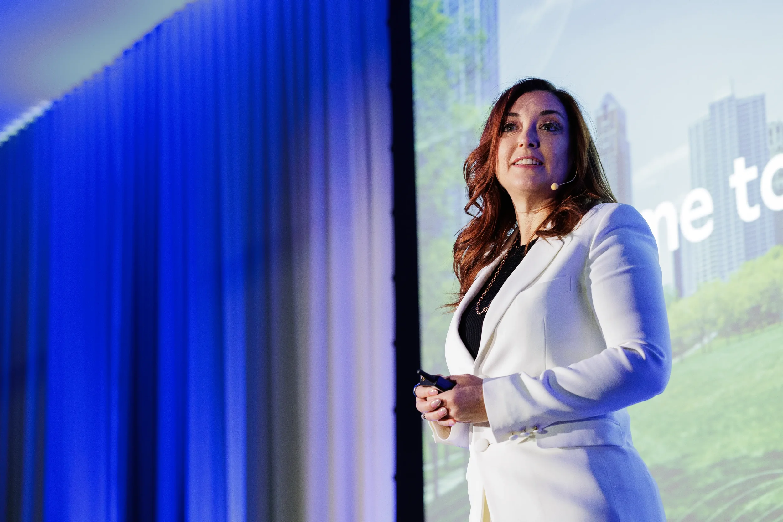Speaker with headset microphone presents on stage holding slide clicker at Chicago industry conference