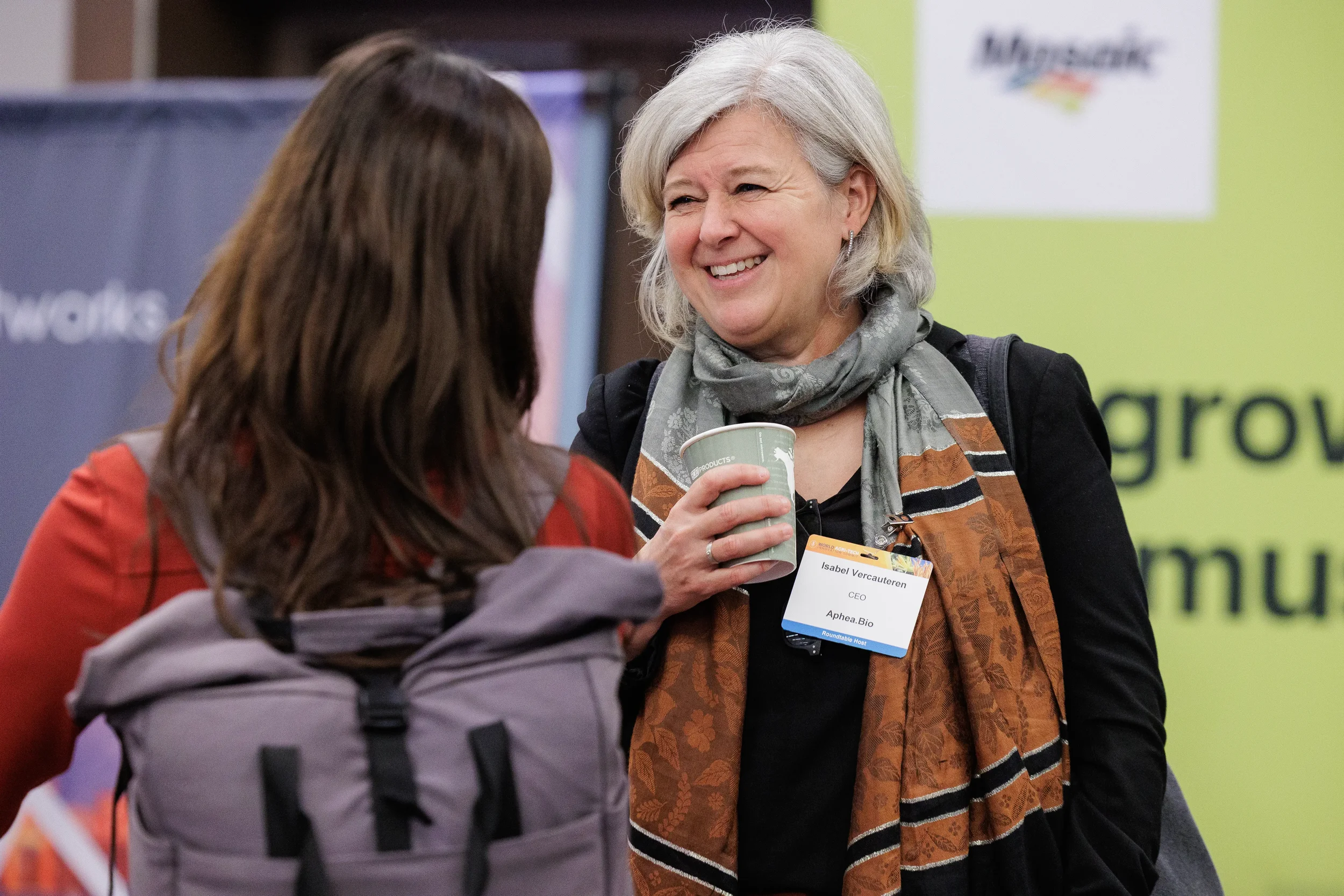 Attendee with name badge holds coffee cup and smiles during conversation on Orlando industry conference expo floor
