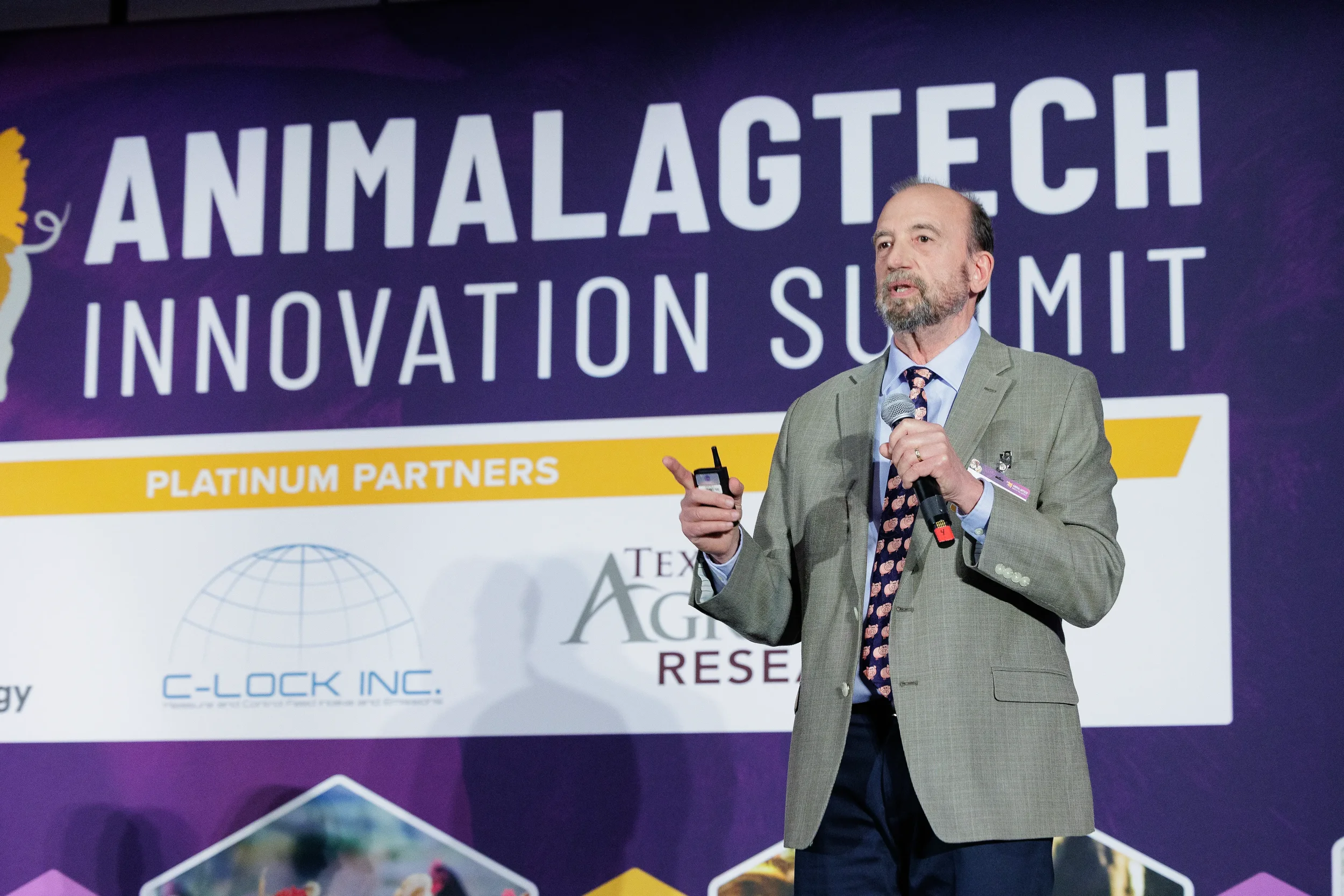 Speaker presents with microphone on branded stage at Orlando industry summit