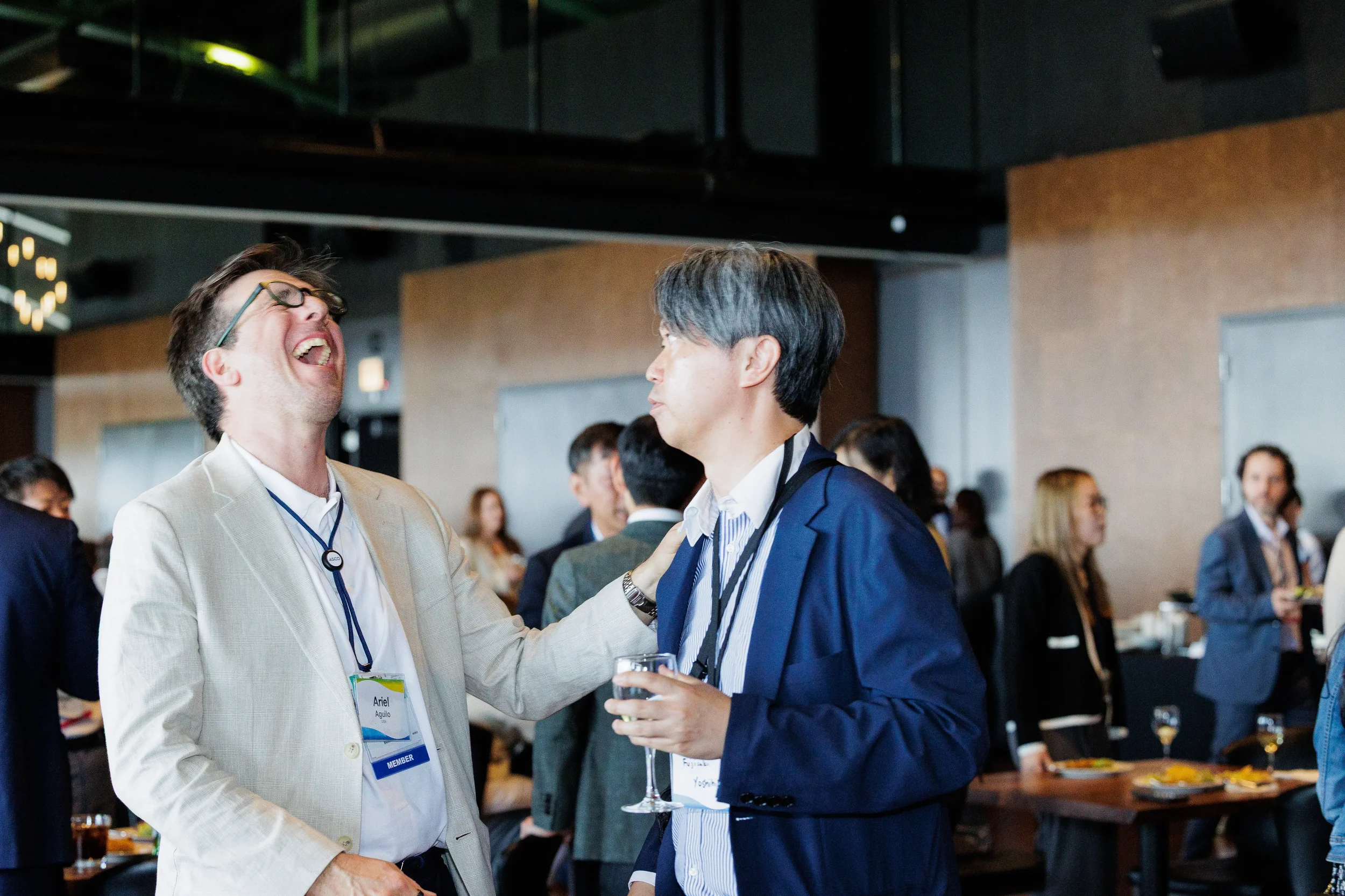 Two attendees share a hearty laugh at networking reception with drinks at Chicago corporate event