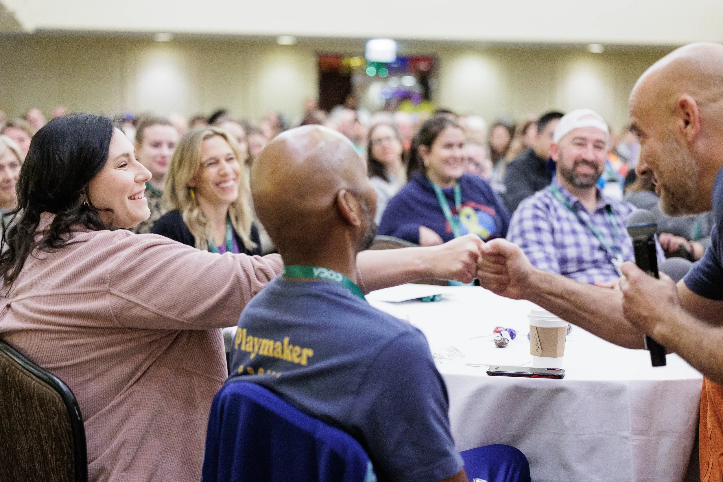 Two attendees share a fist bump while audience smiles in background at Orlando nonprofit conference