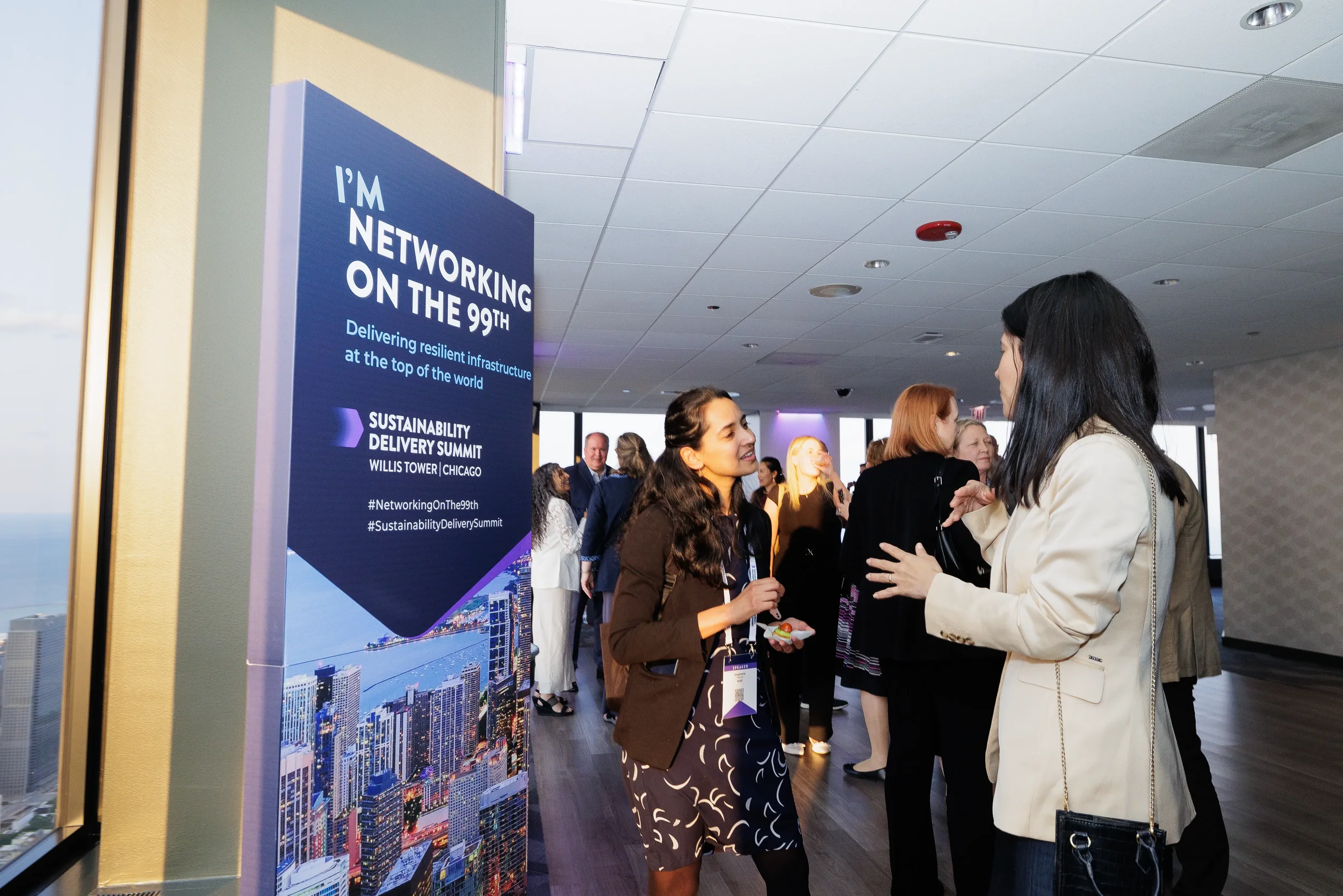 Attendees converse near event signage during networking reception at Orlando industry conference