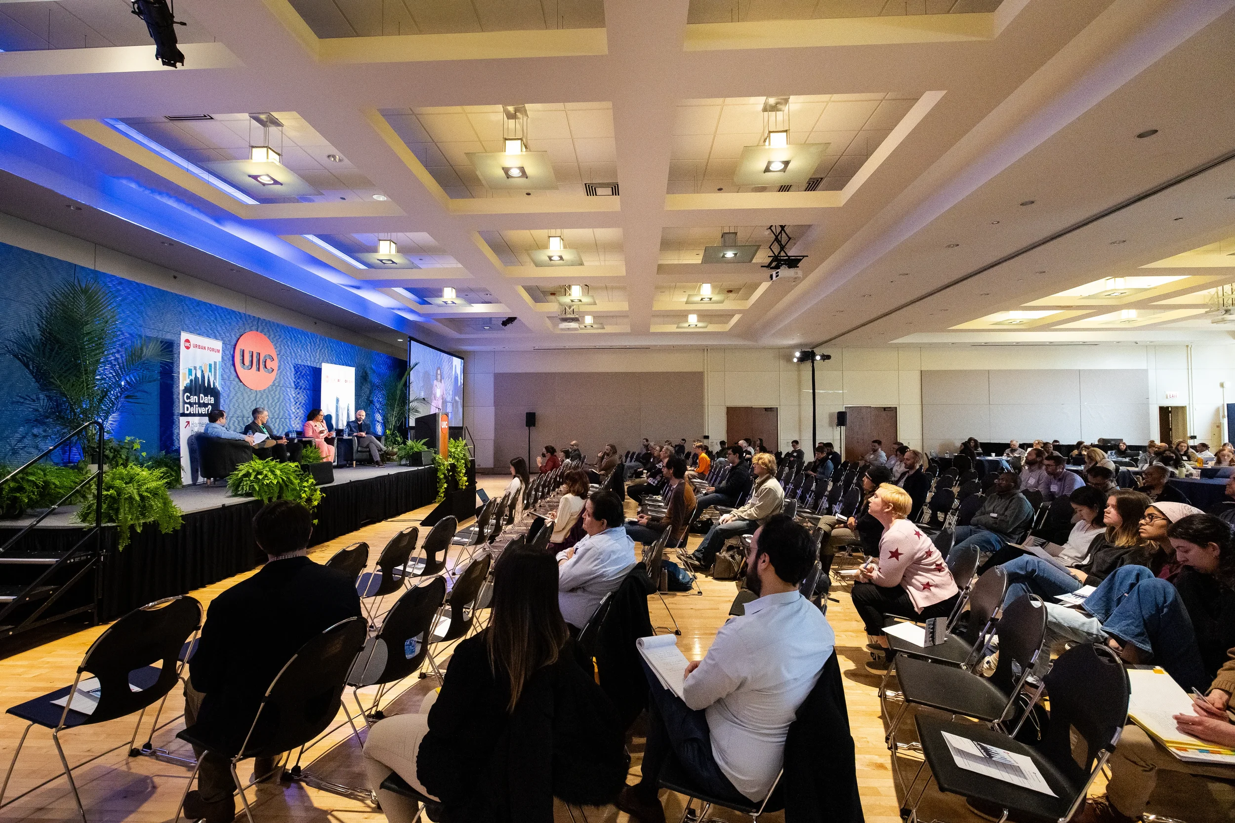Wide view of seated audience watching panel discussion on stage at Chicago corporate conference