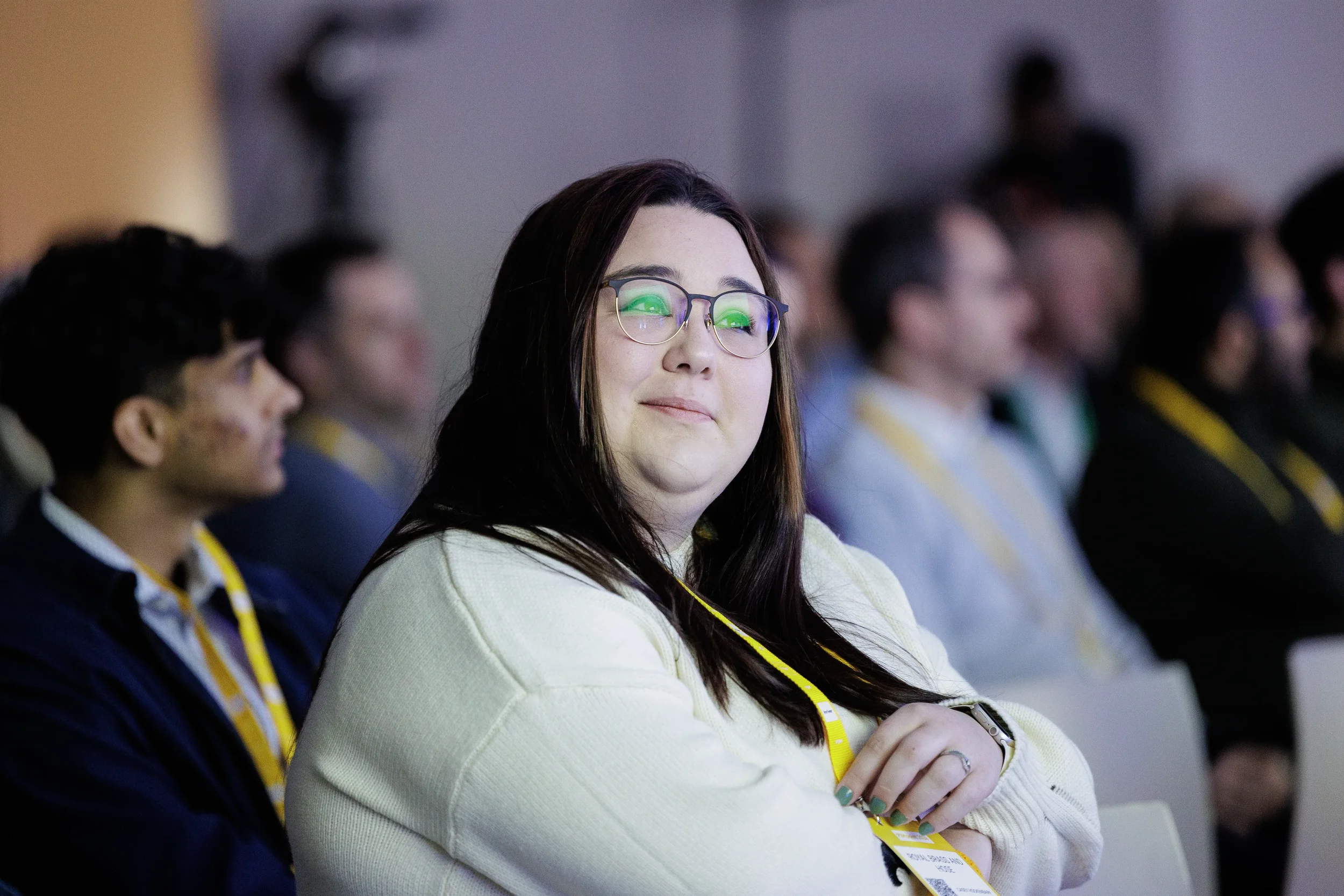 Attendee in yellow lanyard smiles while watching session at Chicago industry conference