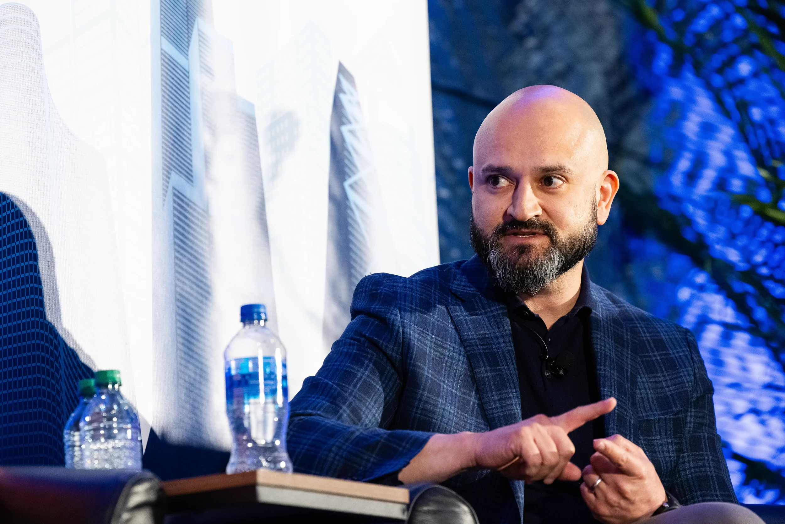 Panelist gestures while speaking on stage with blue backdrop at Chicago industry conference