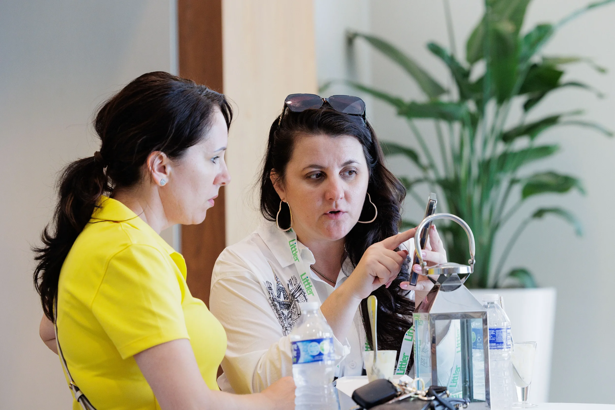 Two female attendees with lanyards engage in focused conversation at table during Chicago industry conference