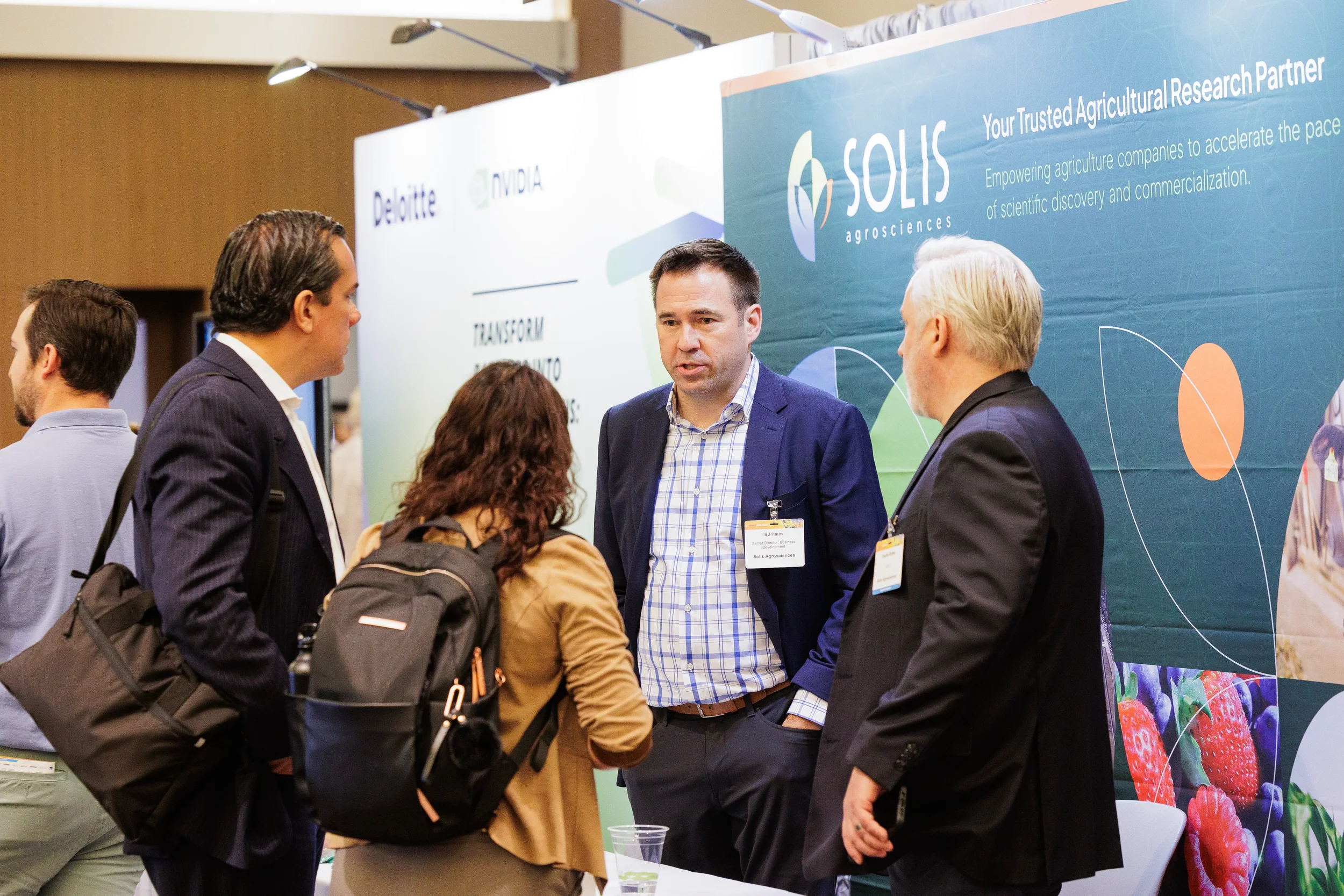 Attendees with name badges converse at exhibitor booth on trade show floor at Chicago industry conference