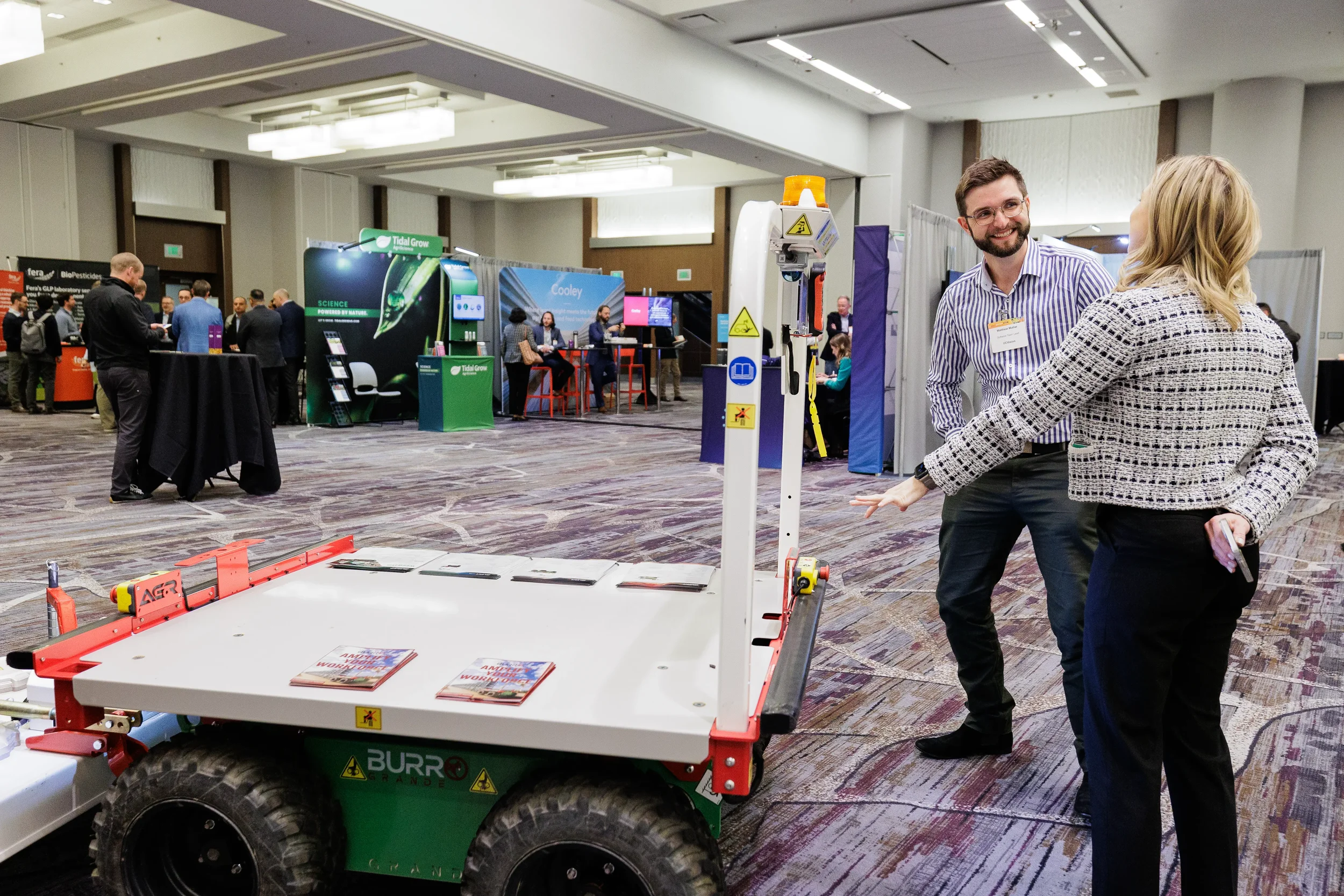 Attendees view autonomous agricultural robot on display at Orlando industry conference trade show floor