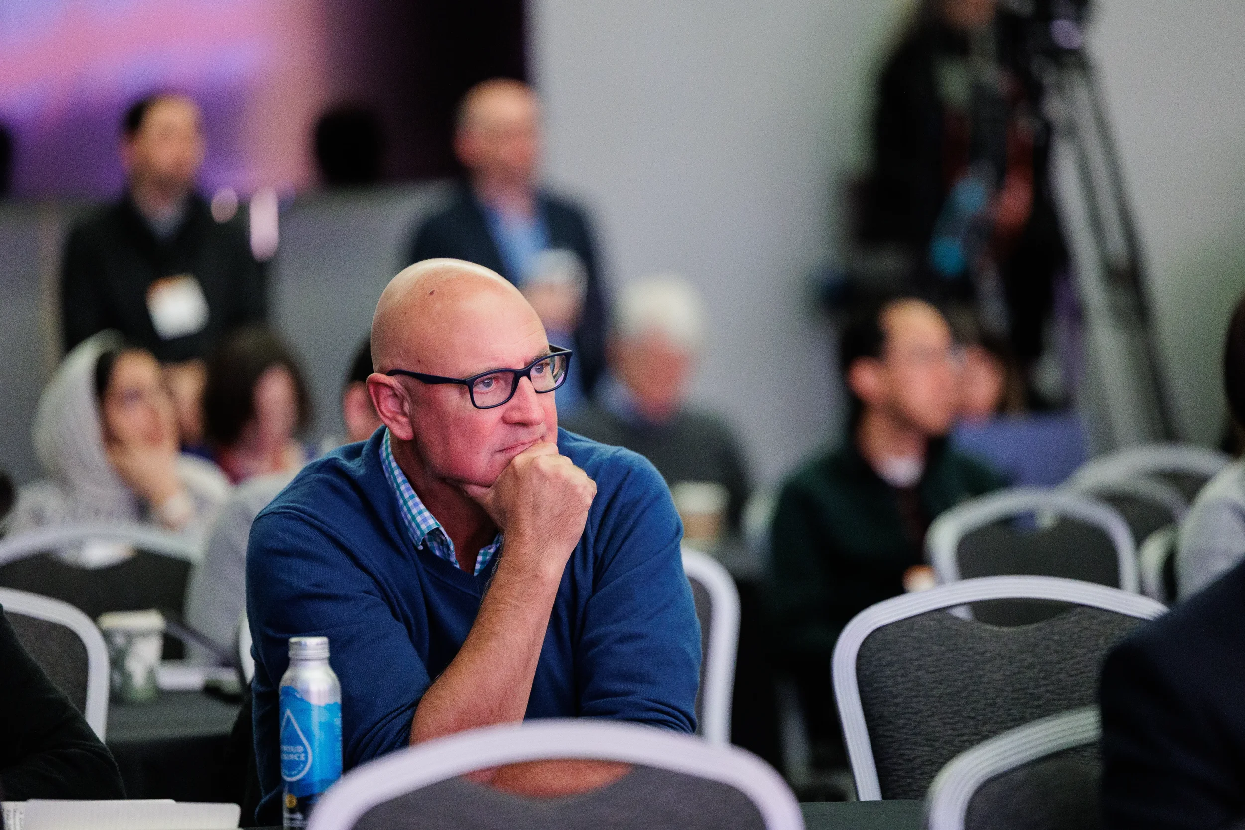 Attendee with glasses listens intently with hand on chin during session at Chicago industry conference