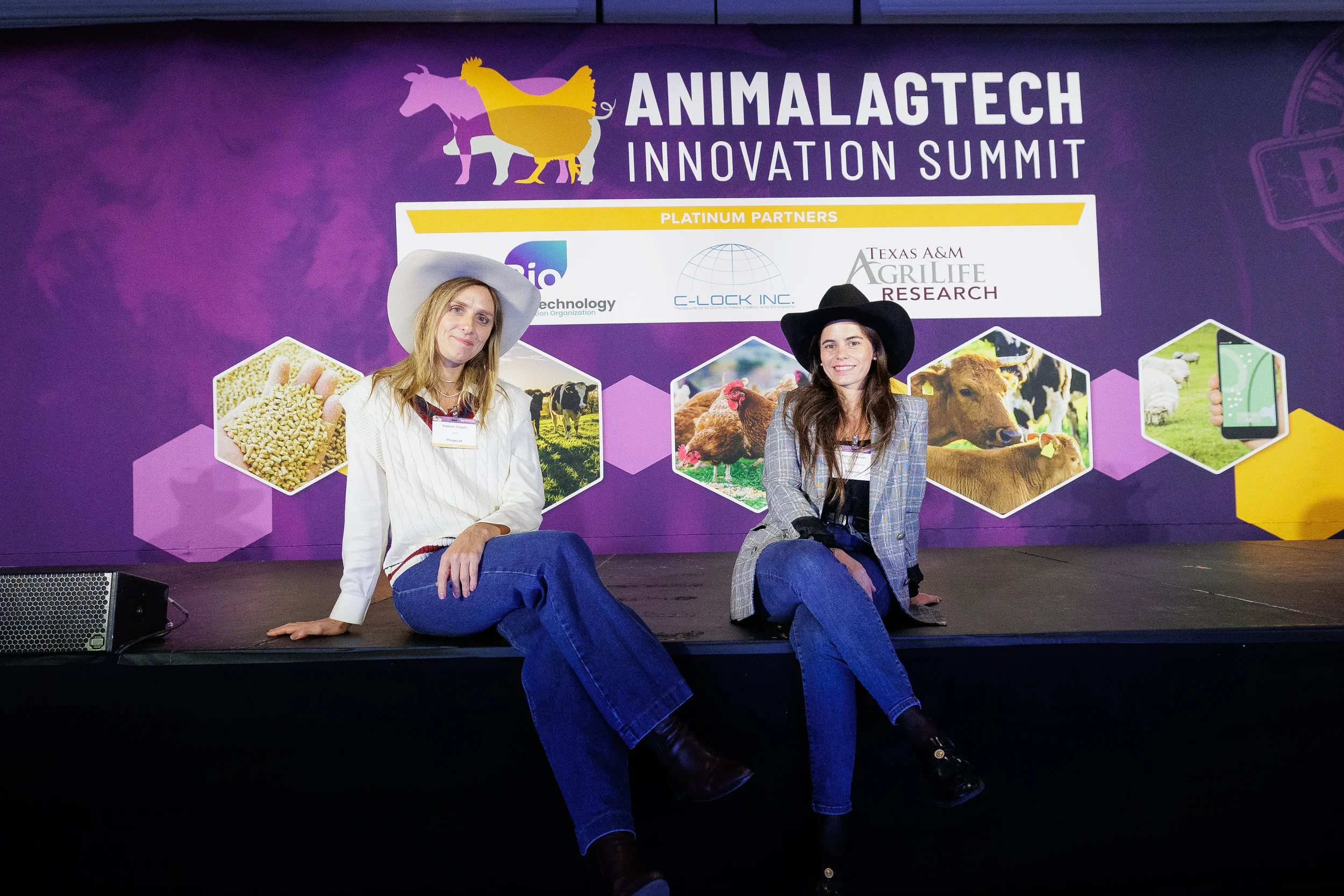 Two attendees in cowboy hats pose seated on branded stage at Orlando industry summit