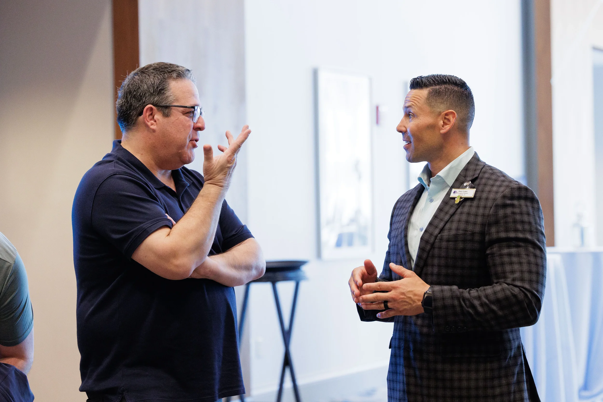 Two male attendees in animated conversation with name badge visible at Chicago corporate conference