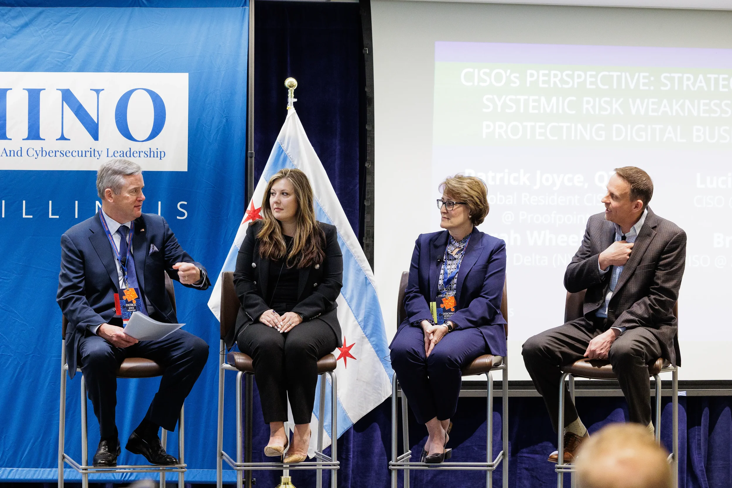 Four panelists seated on stage with Chicago flag during industry panel discussion at Chicago corporate event