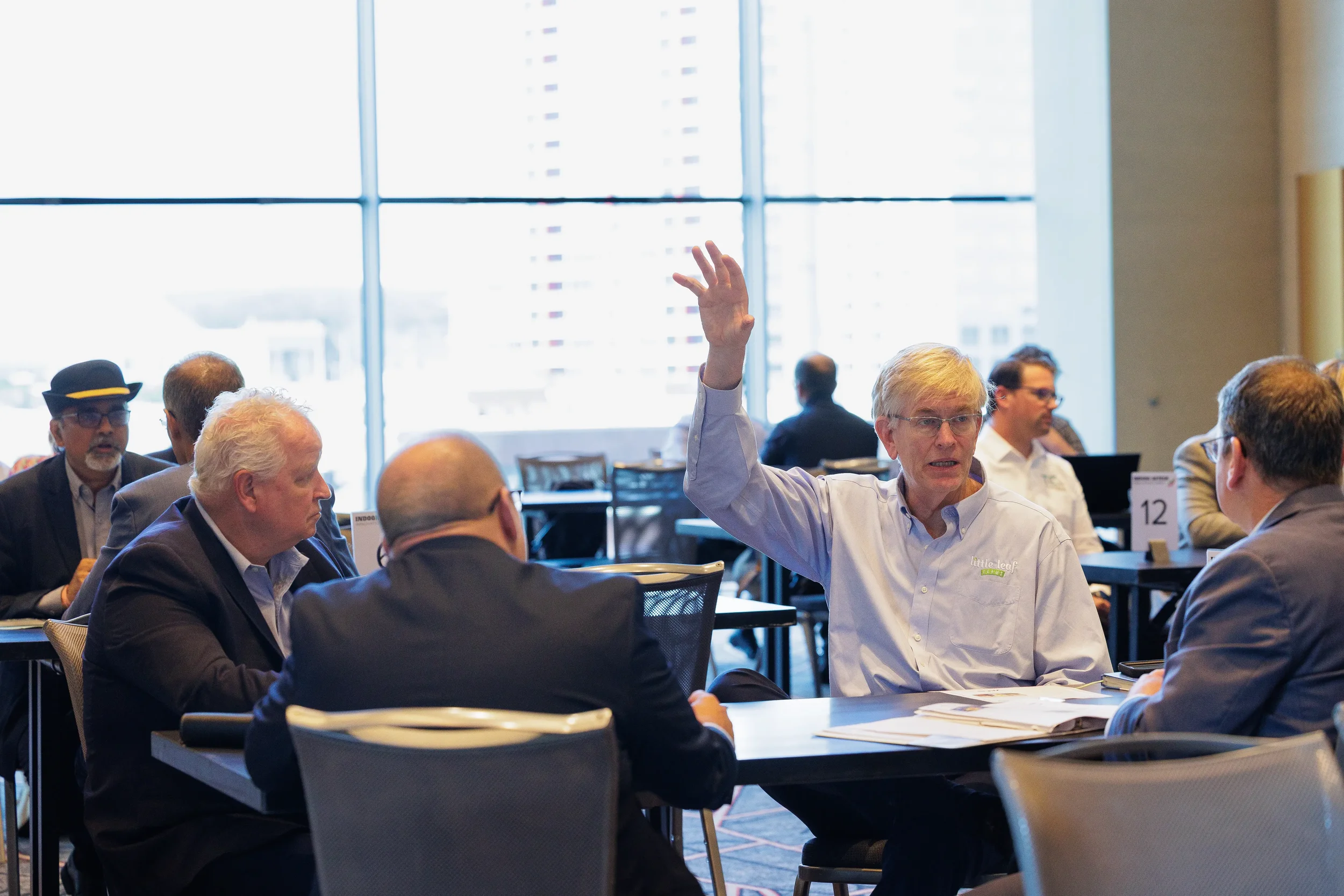 Attendee raises hand while seated at roundtable discussion during Chicago industry conference event