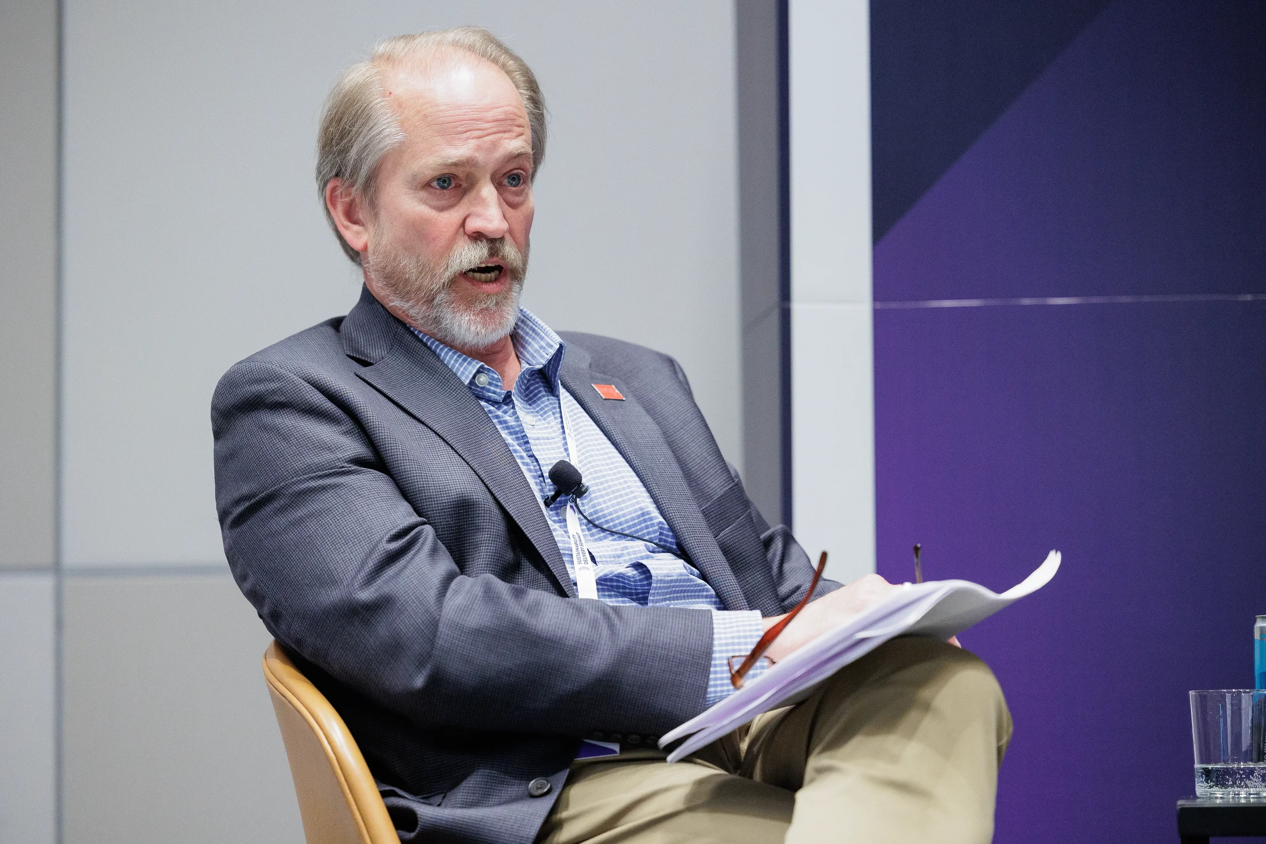 Speaker gestures while seated on panel holding notes at Chicago industry conference session