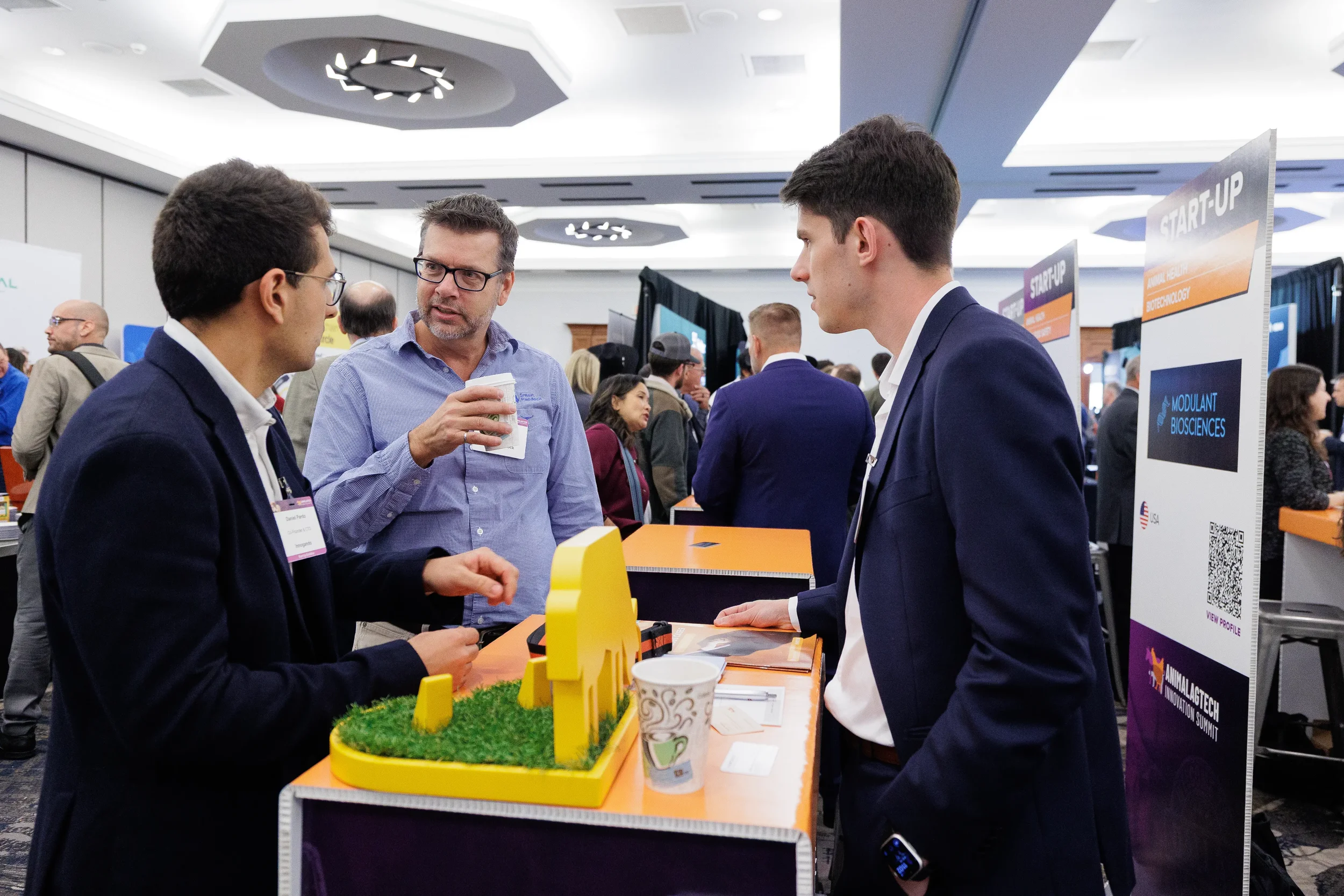 Attendees converse near startup exhibitor booths on expo floor at Chicago corporate conference