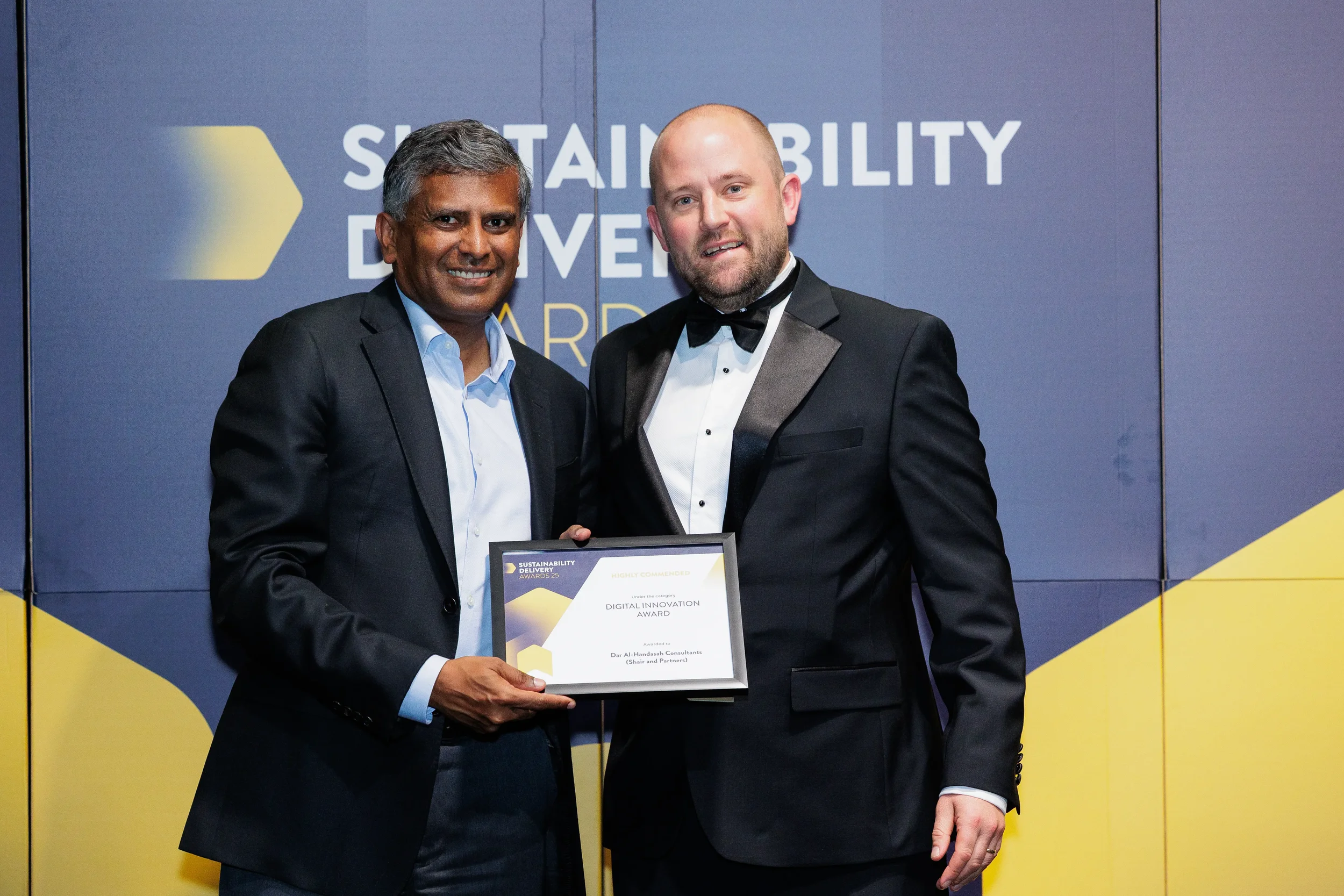 Two men pose with award plaque on stage during Orlando corporate event awards presentation