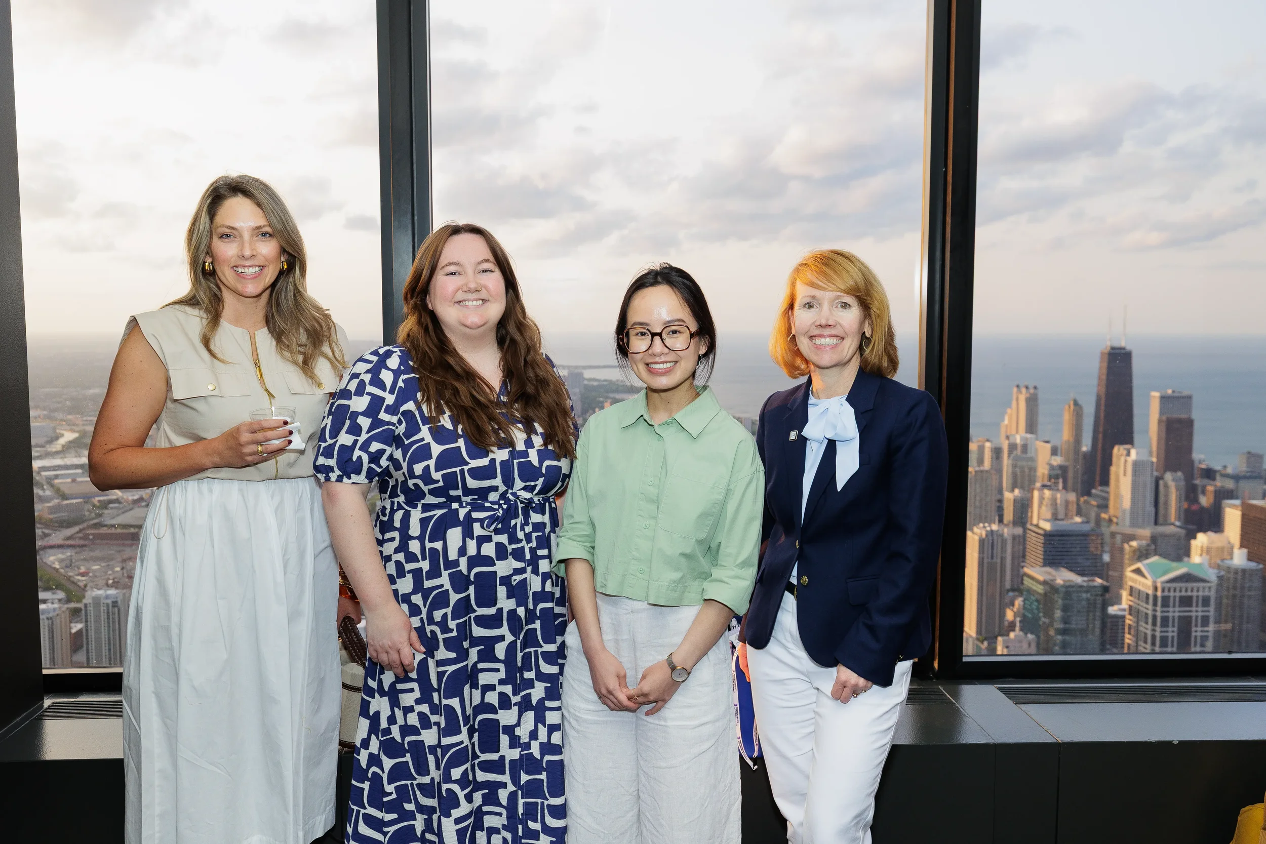 Four attendees smile for group photo with skyline view at Orlando corporate conference reception
