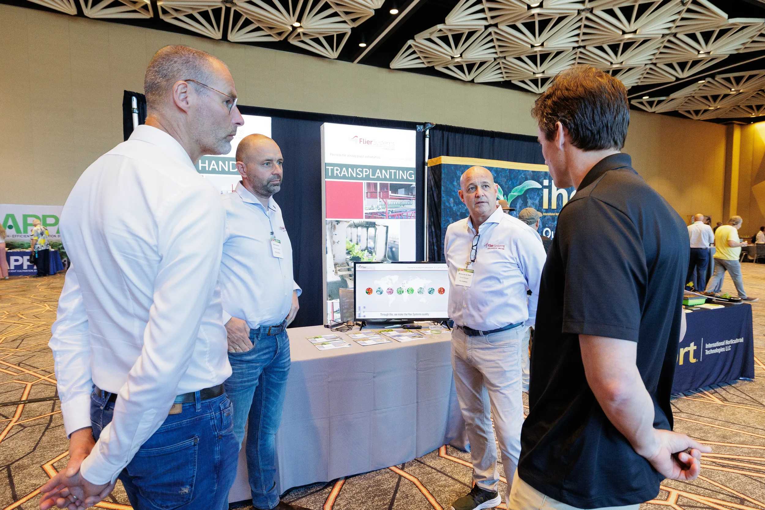 Attendee speaks with exhibitors at trade show booth during expo floor networking at Orlando industry conference