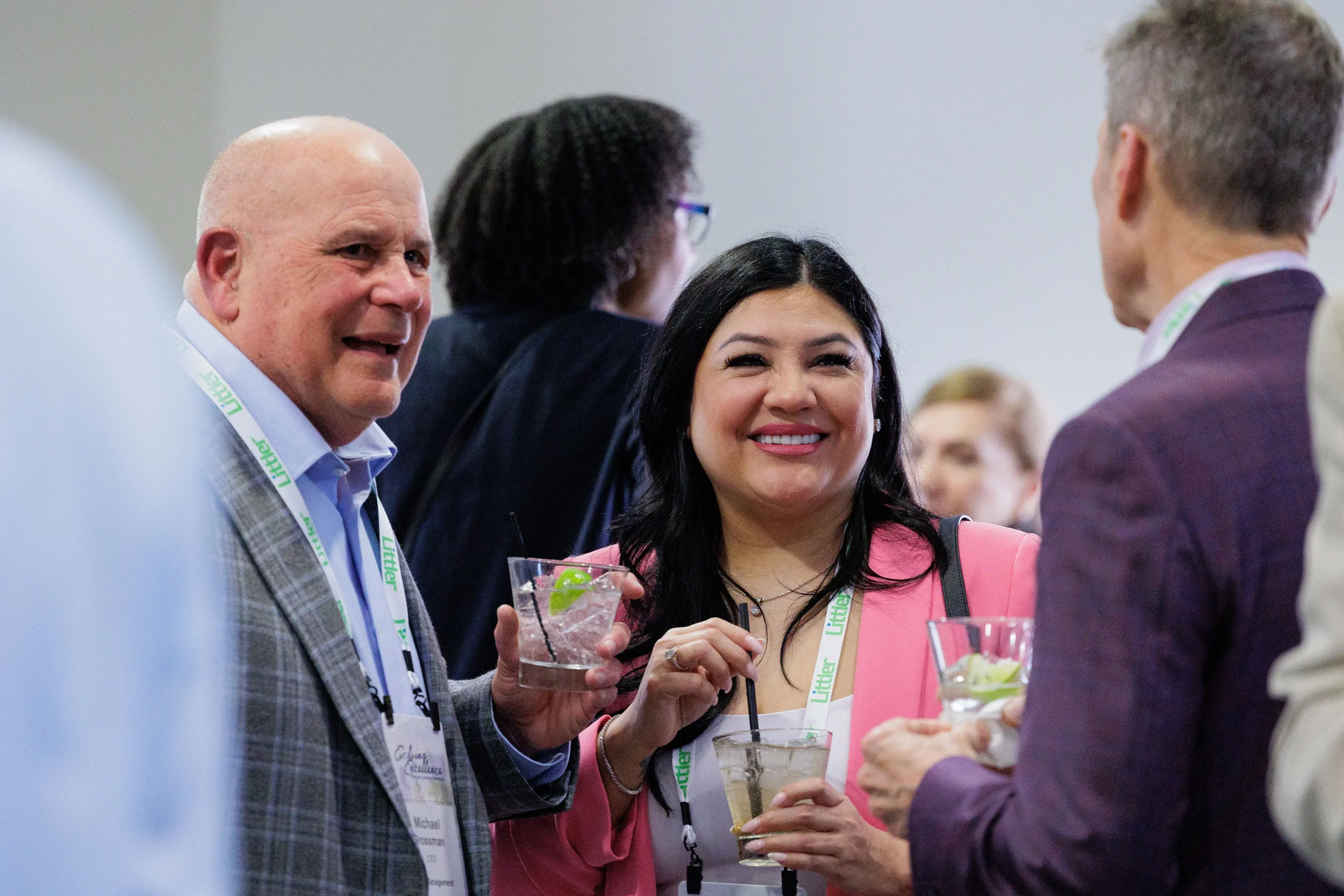 Three attendees with lanyards laugh and network over cocktails at Chicago corporate event reception