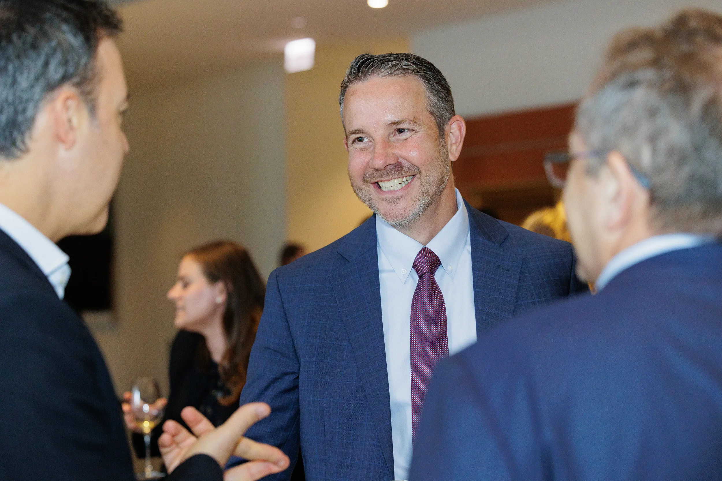 Attendee smiles while conversing with colleagues during Orlando corporate conference reception