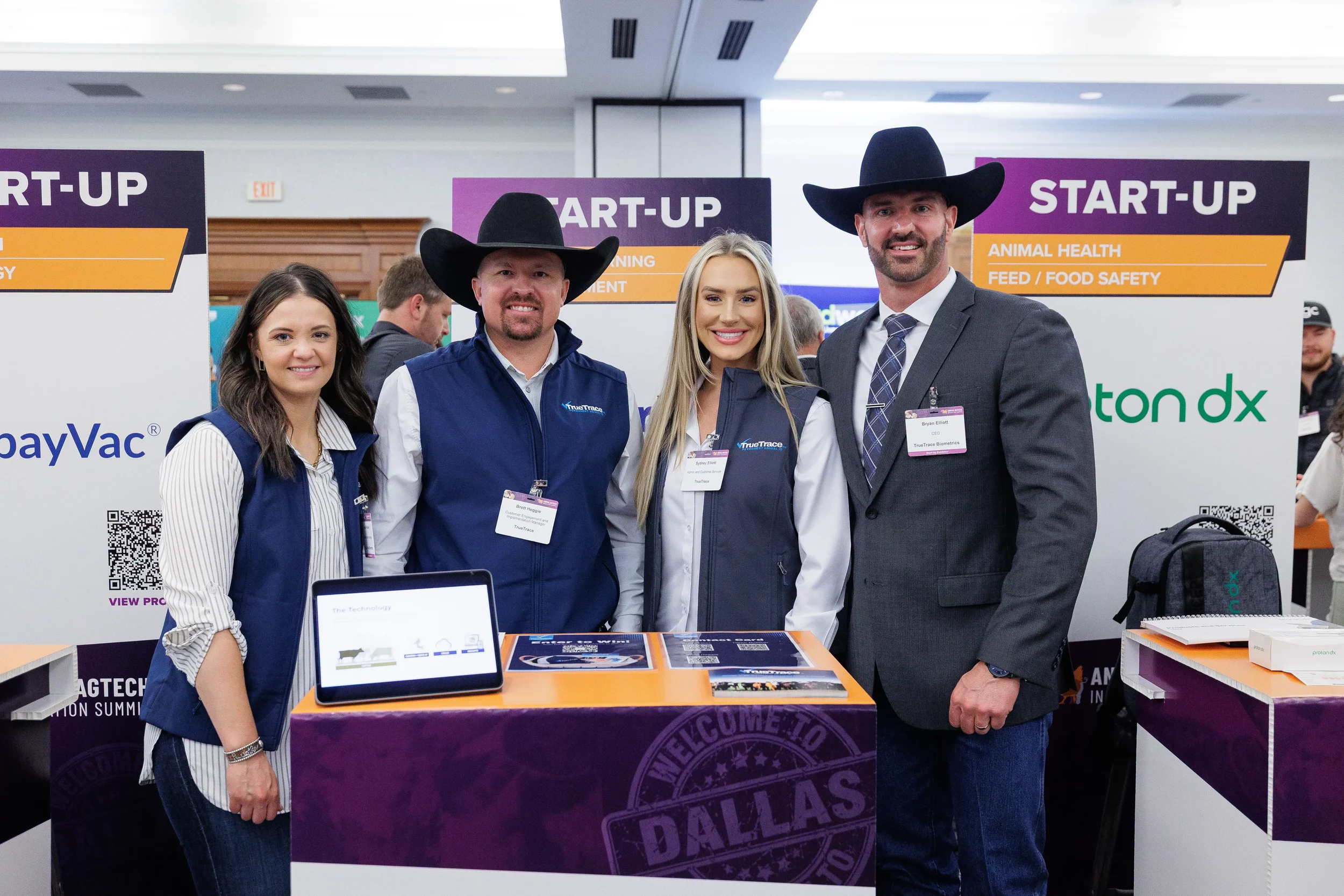 Four attendees including two in cowboy hats pose at expo booth during Chicago conference