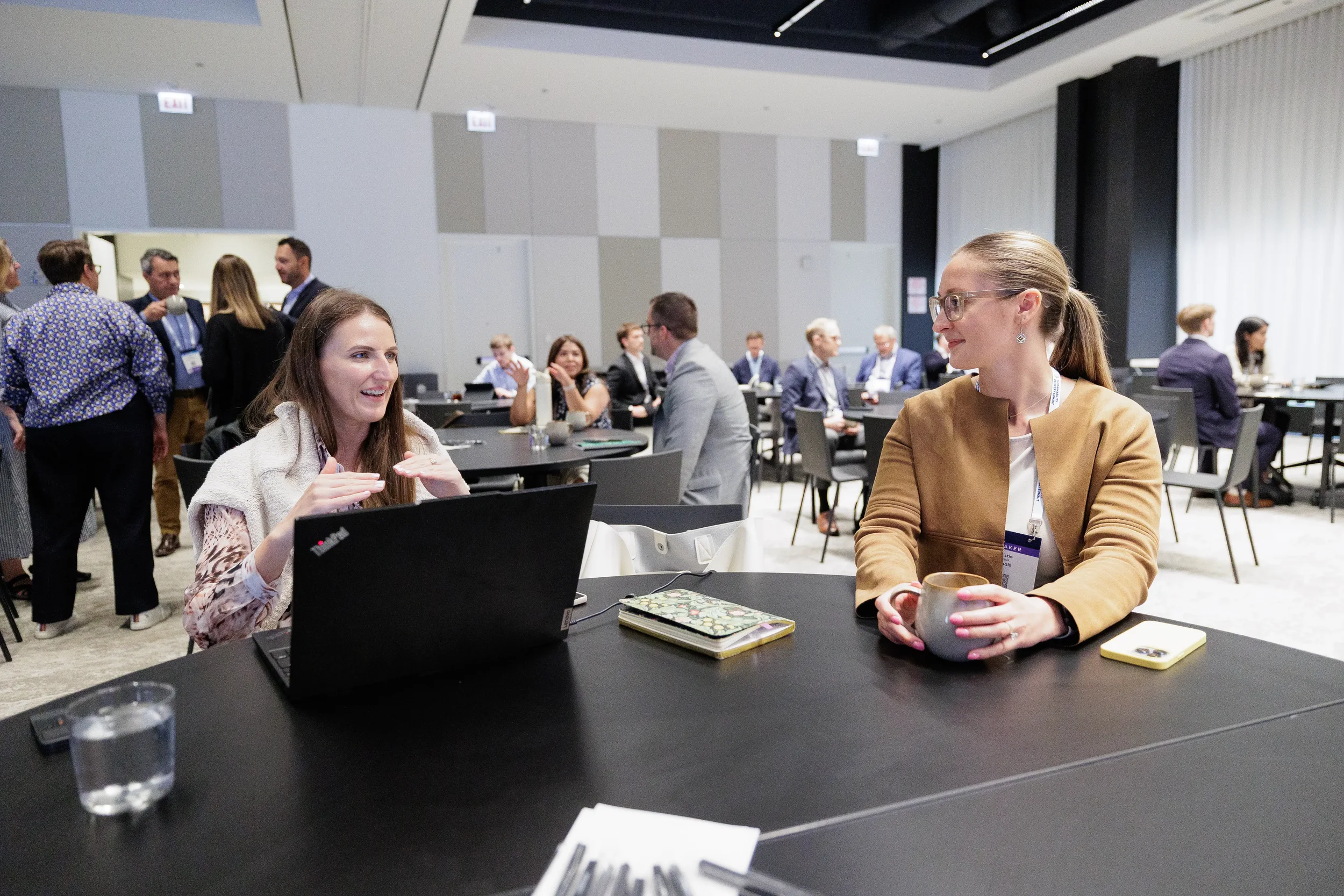 Two attendees converse over coffee and laptop during Chicago corporate conference break