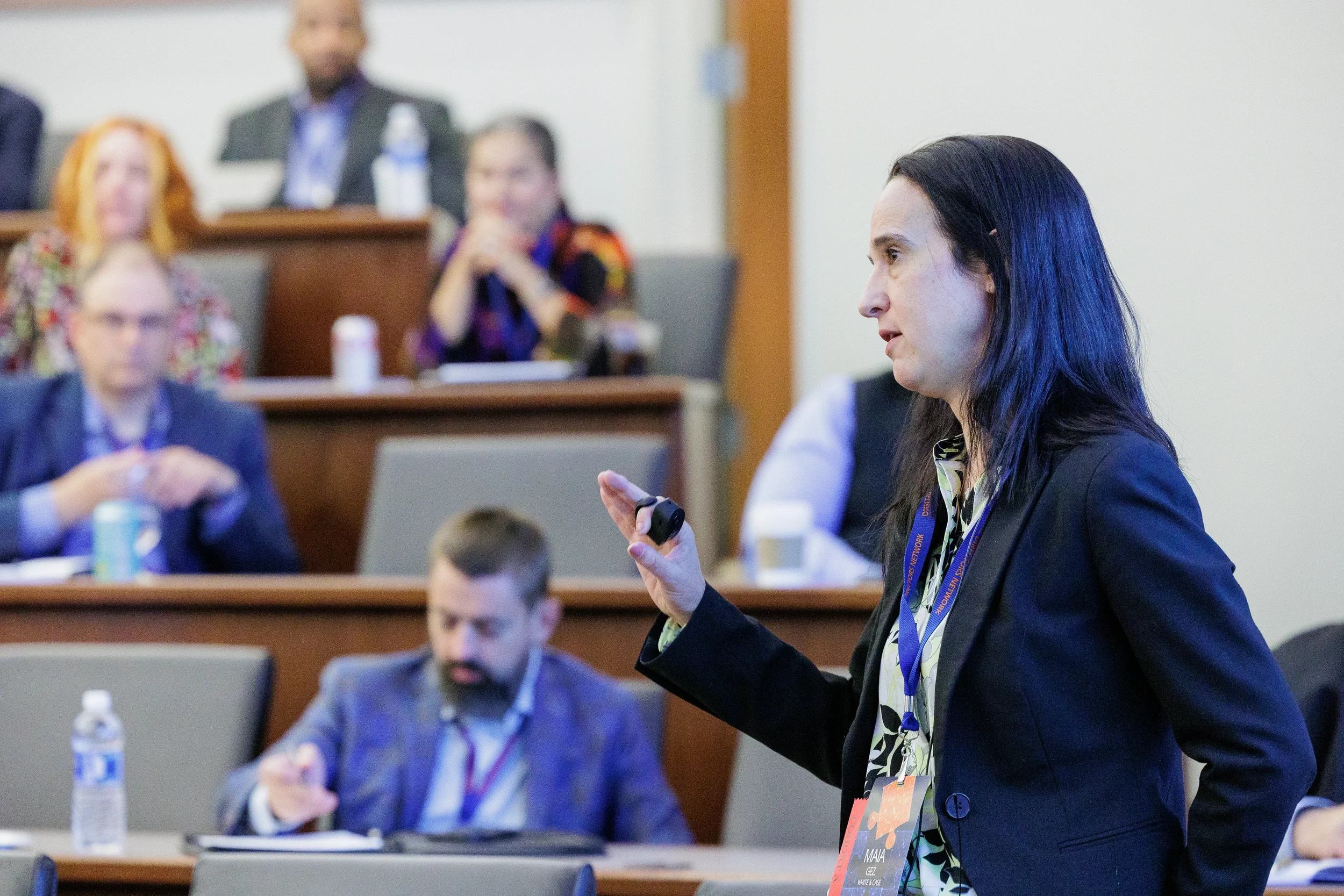 Female speaker with clicker gestures while presenting to tiered audience at Orlando corporate conference