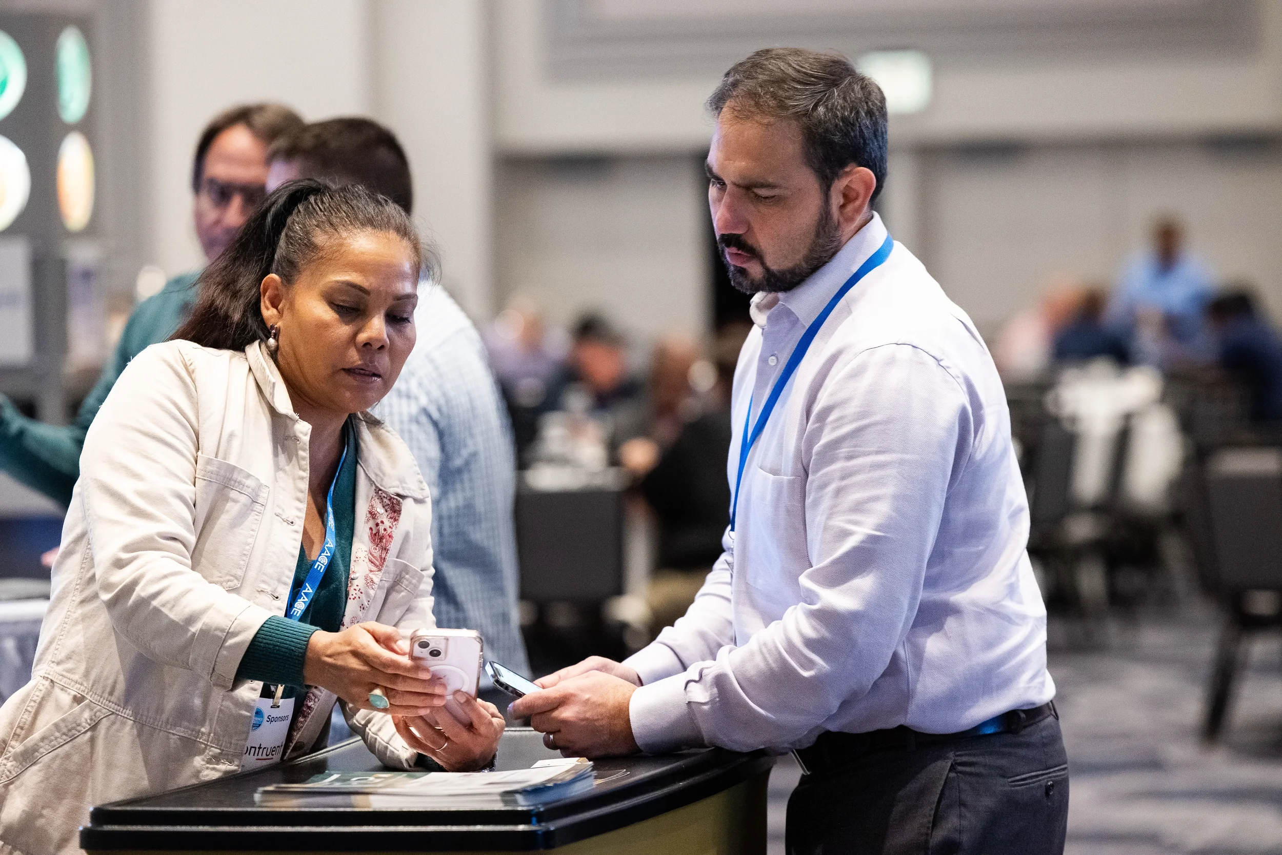 Professionals share phone screens while networking at Chicago corporate conference expo hall